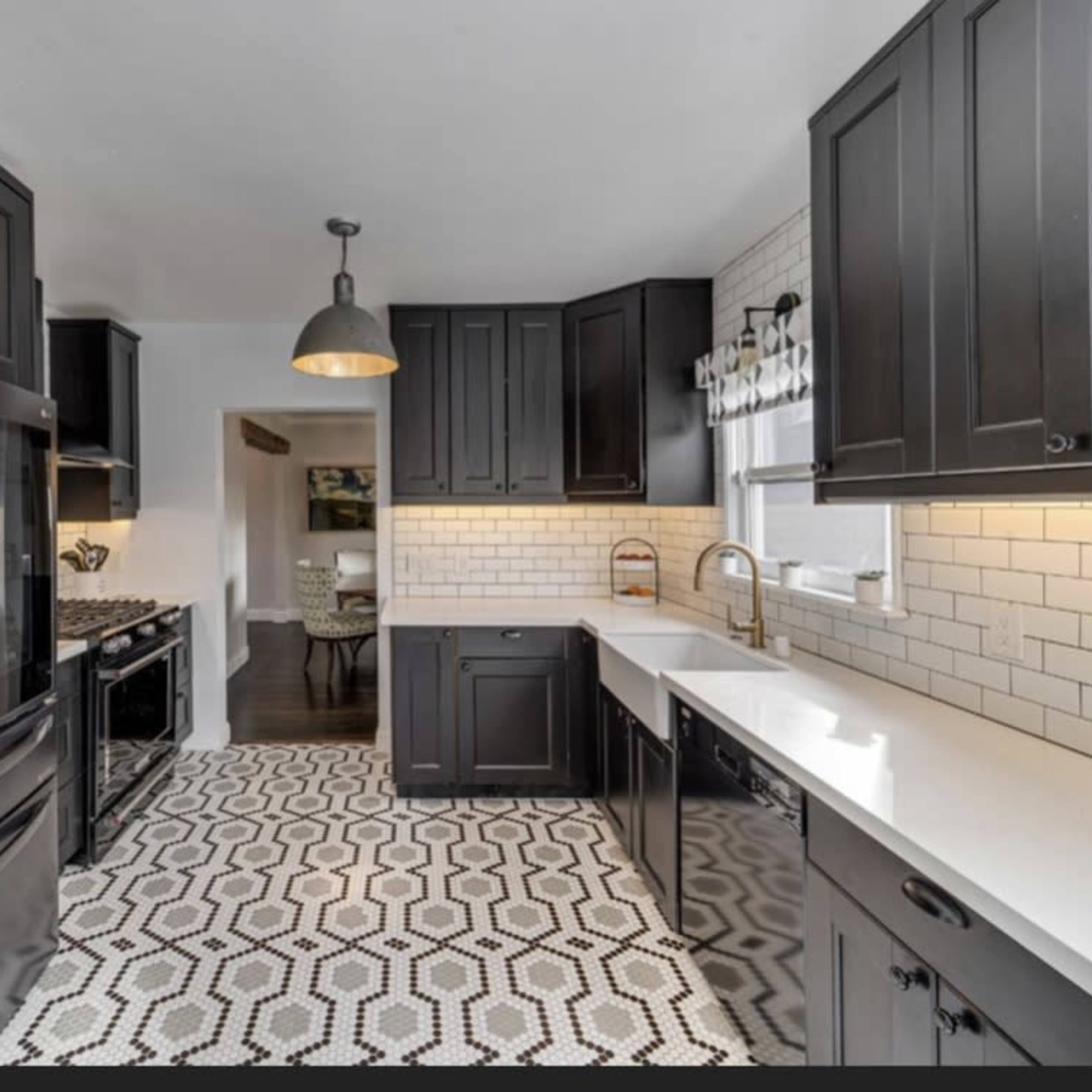 A modern kitchen features black cabinetry, stainless steel appliances, and a patterned tile floor.