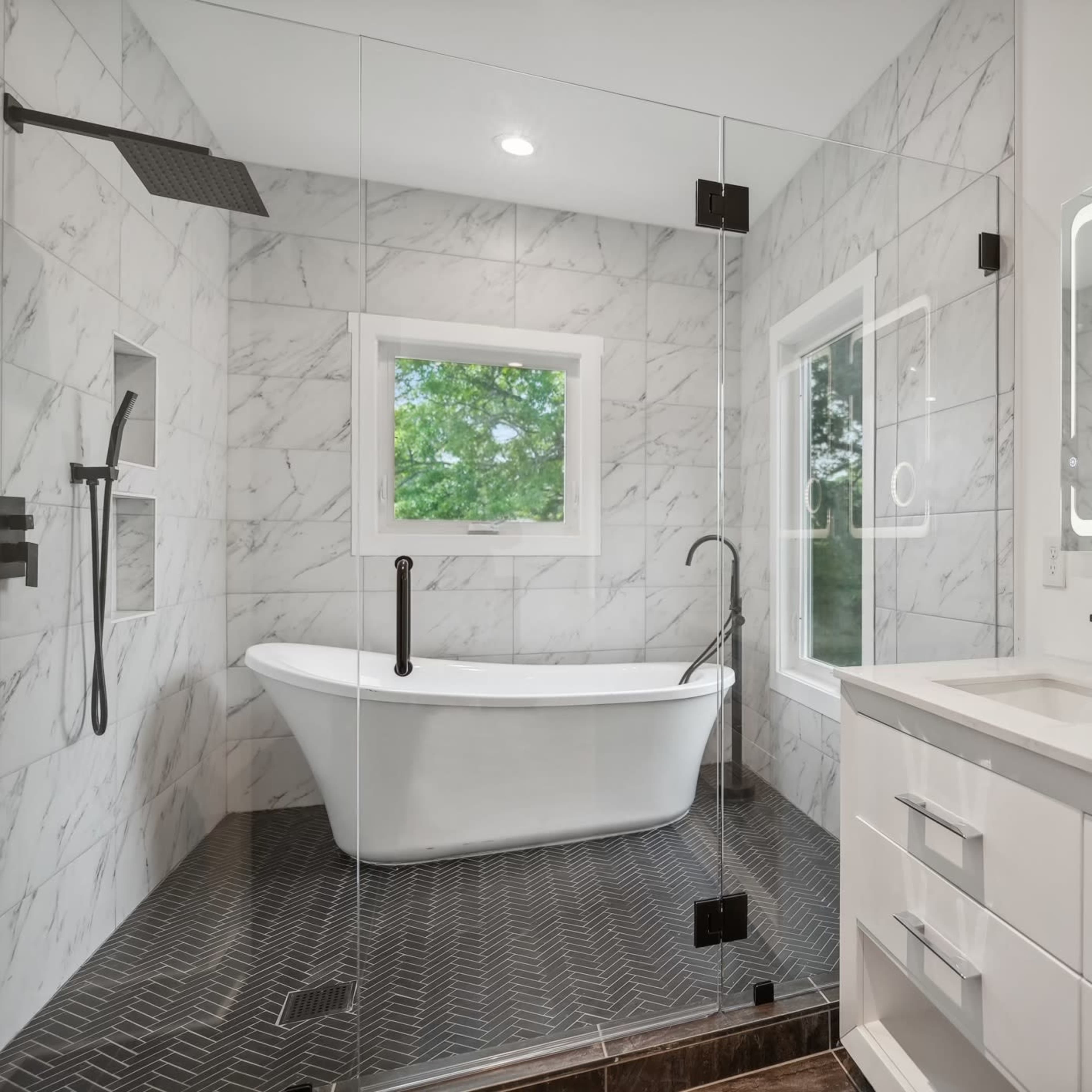 A modern bathroom featuring a freestanding bathtub, a glass shower enclosure, and dual rectangular mirrors above a sleek vanity.
