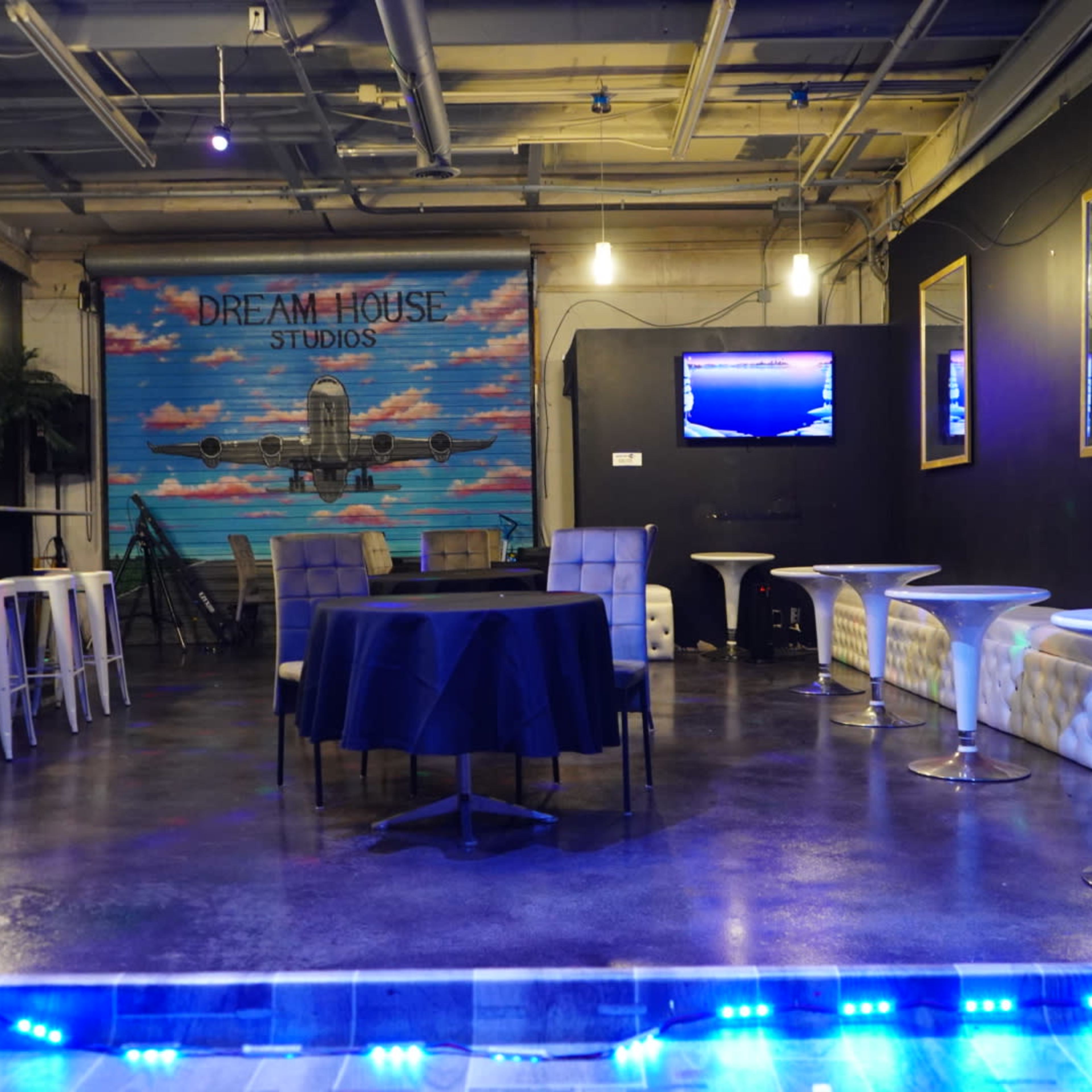 A modern studio space with bar seating, a table in the center, and a colorful mural on the wall.