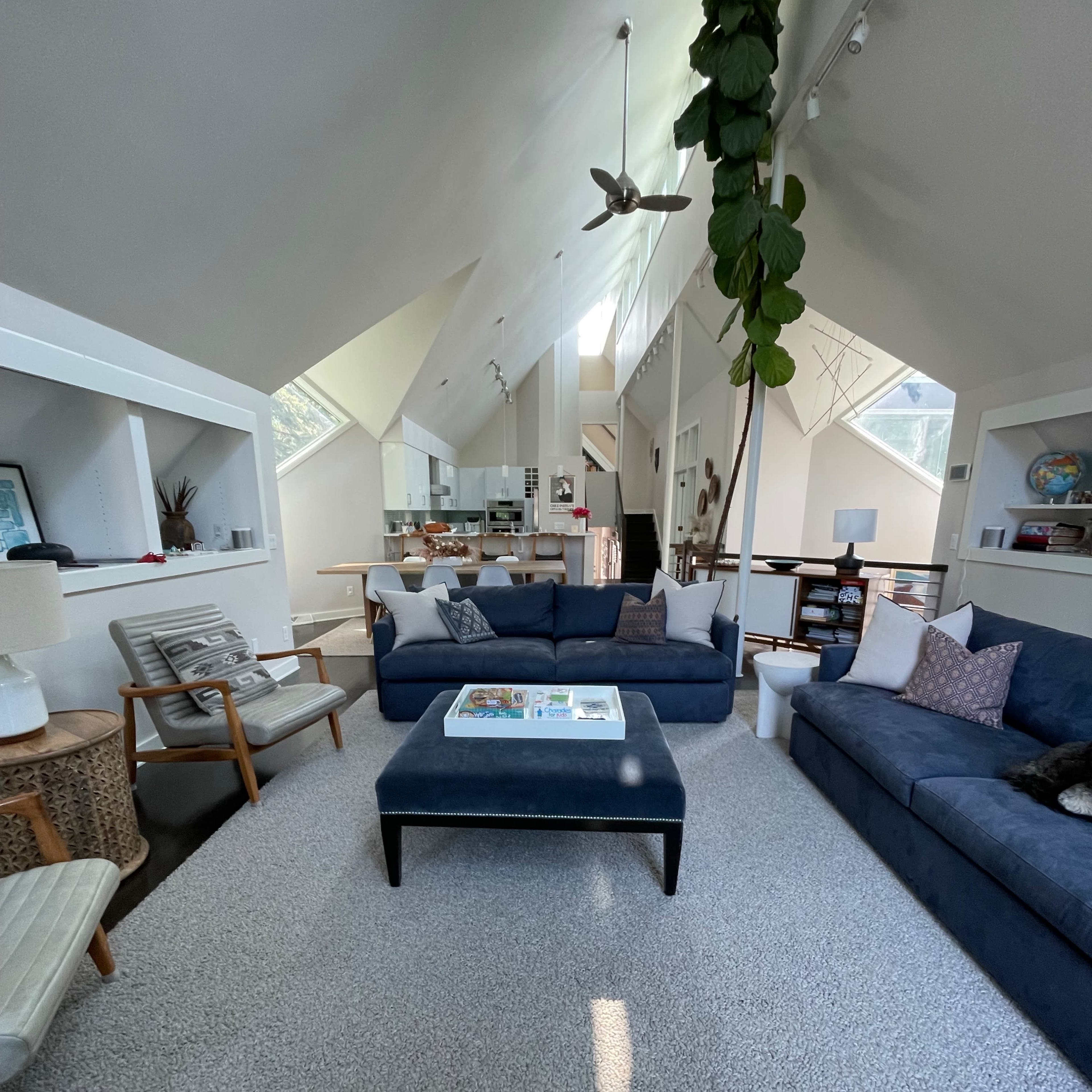 A spacious, modern living room with a blue sofa, a coffee table in the center, and large windows that provide ample natural light.