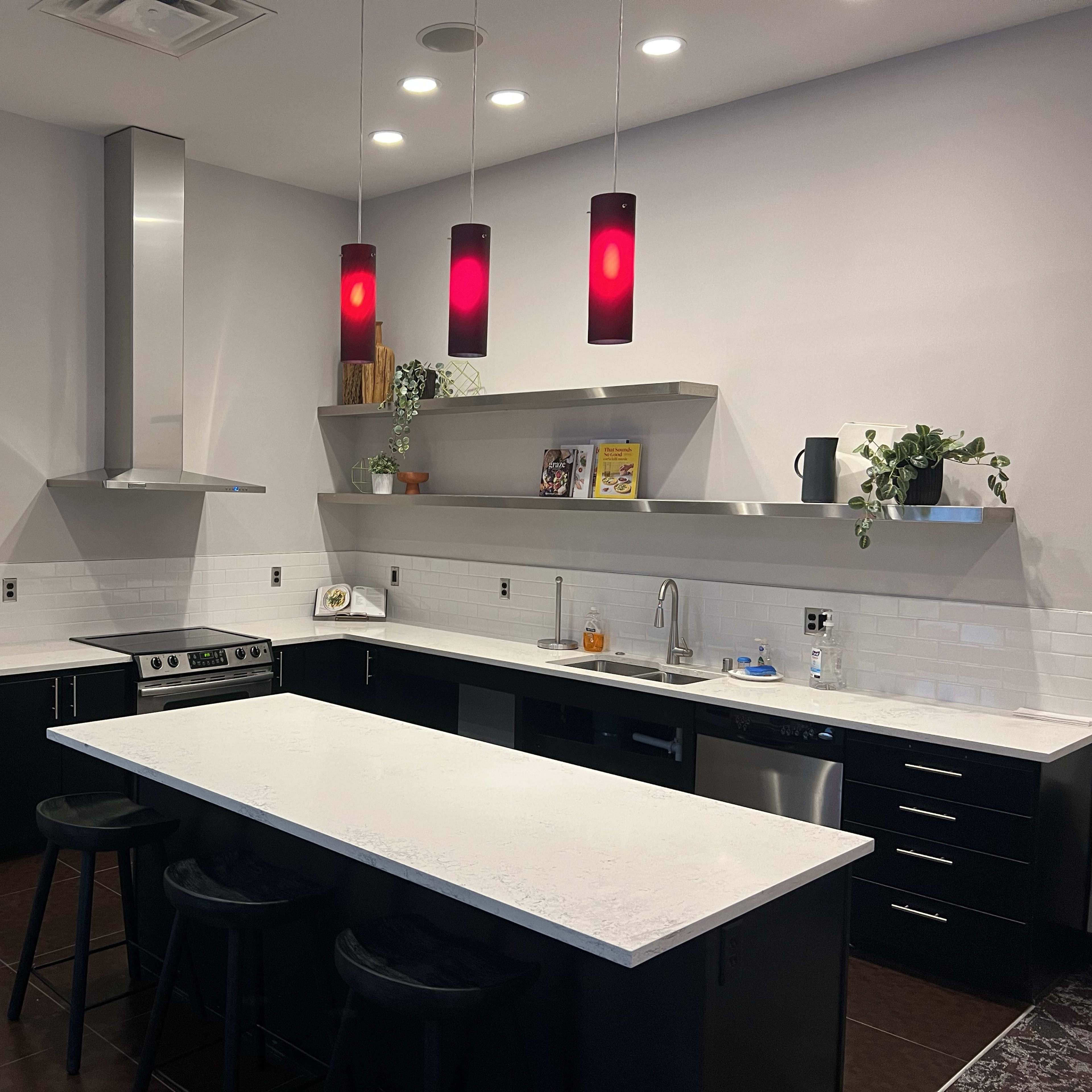 A modern kitchen featuring stainless steel appliances, black cabinets, and a large white island with bar seating.