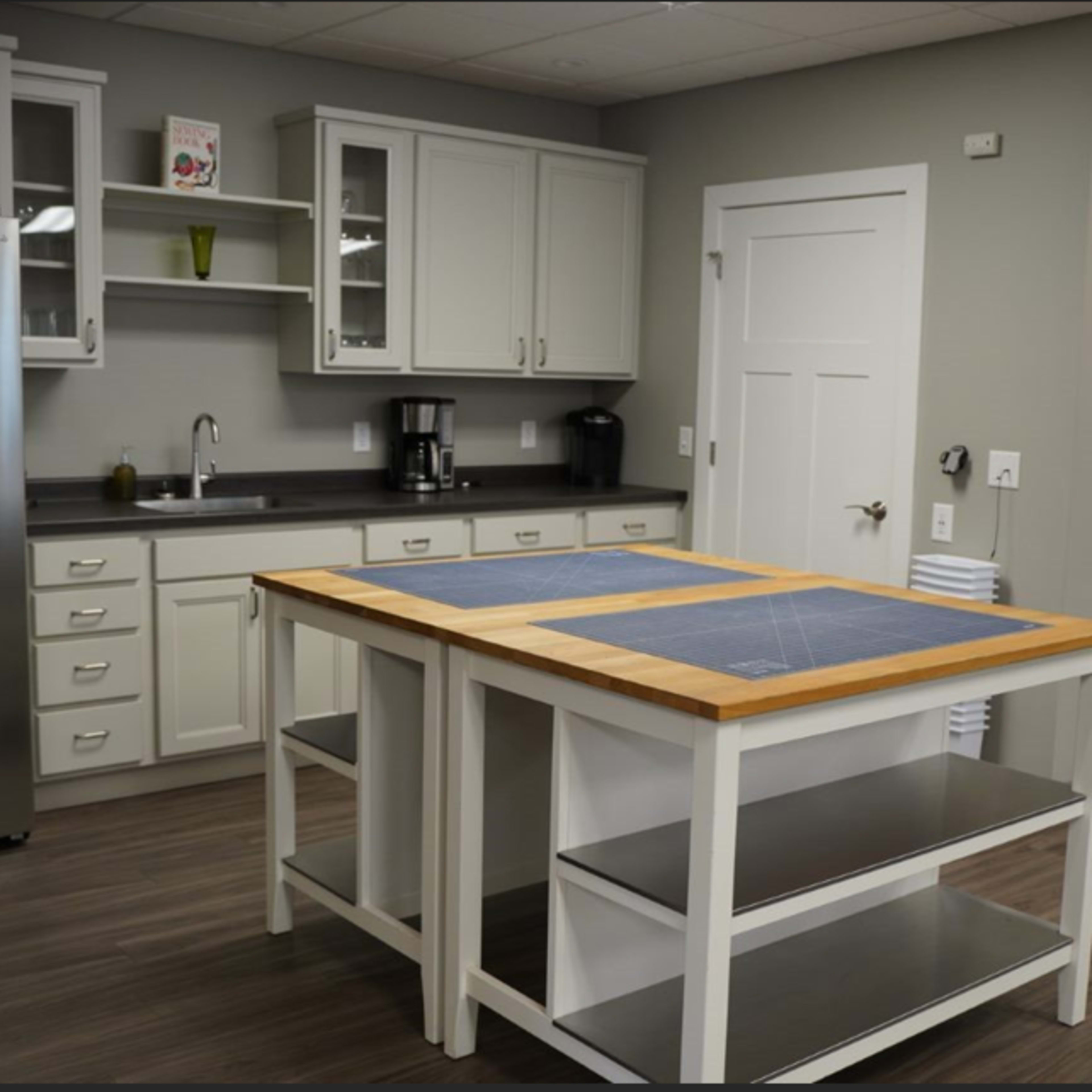 A modern kitchen with a central island, stainless steel appliances, white cabinets, and gray walls.