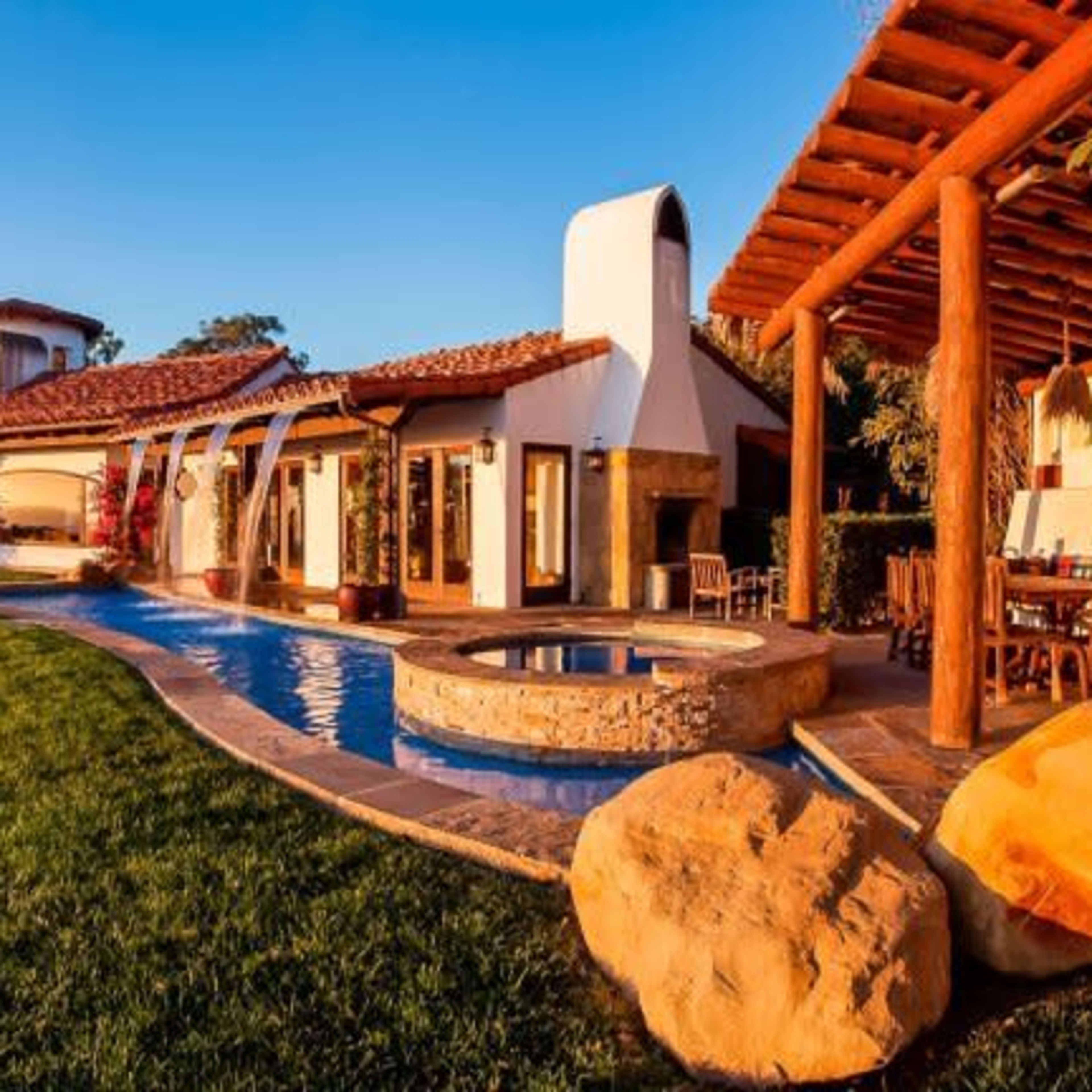 A large coastal villa features a pool, landscaped lawn, and ocean views.