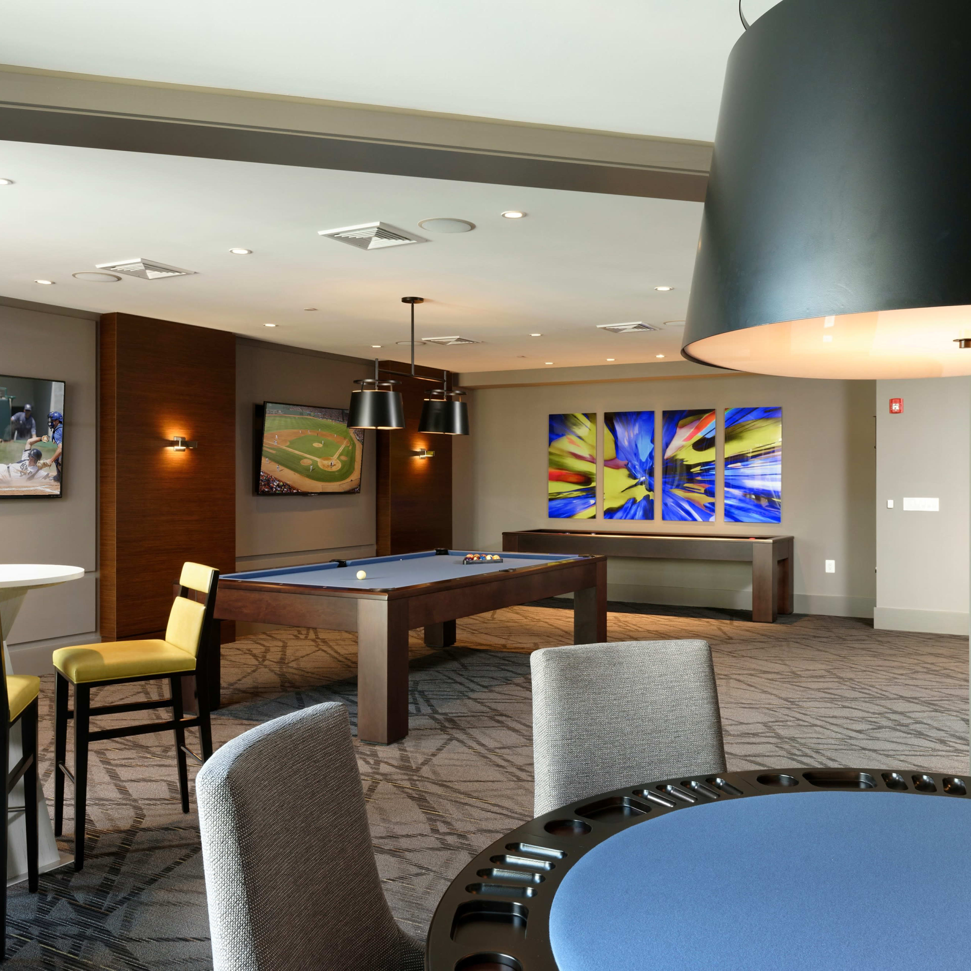 A modern recreational room with a billiard table, contemporary artwork on the walls, and comfortable seating arrangements.