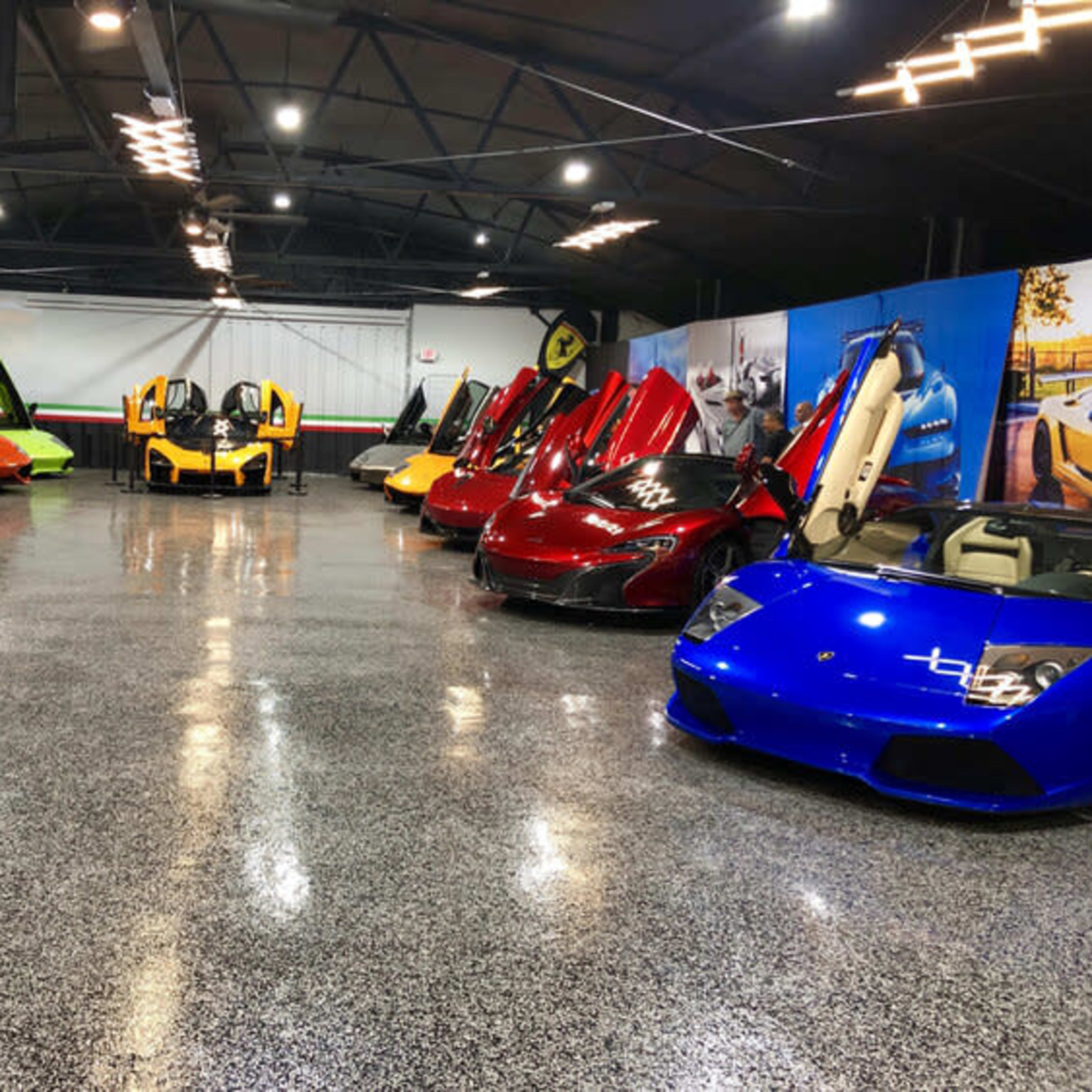A collection of luxury sports cars with their doors open, arranged in a well-lit garage.