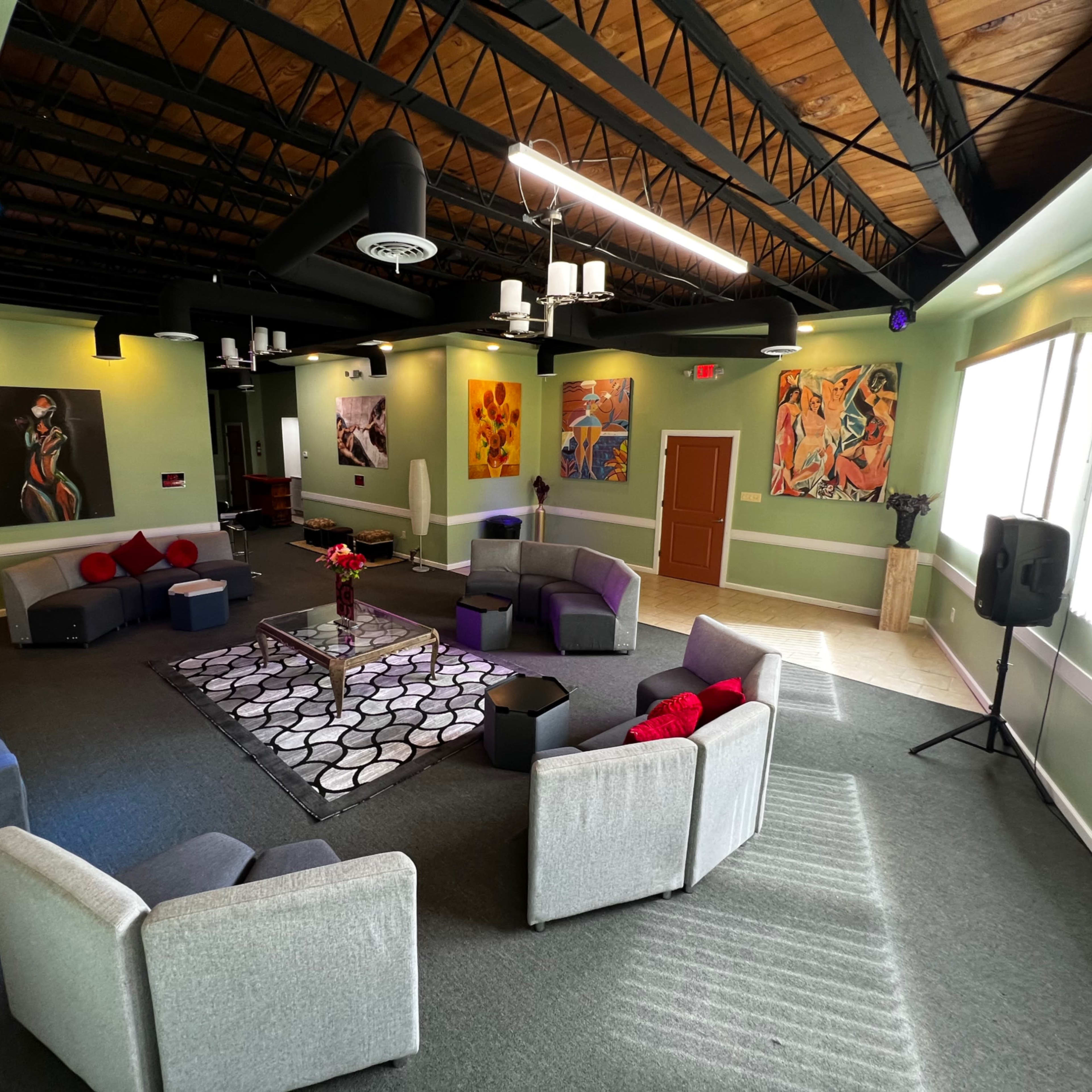 A spacious lounge area furnished with gray chairs, a circular rug, and colorful artwork on the walls.