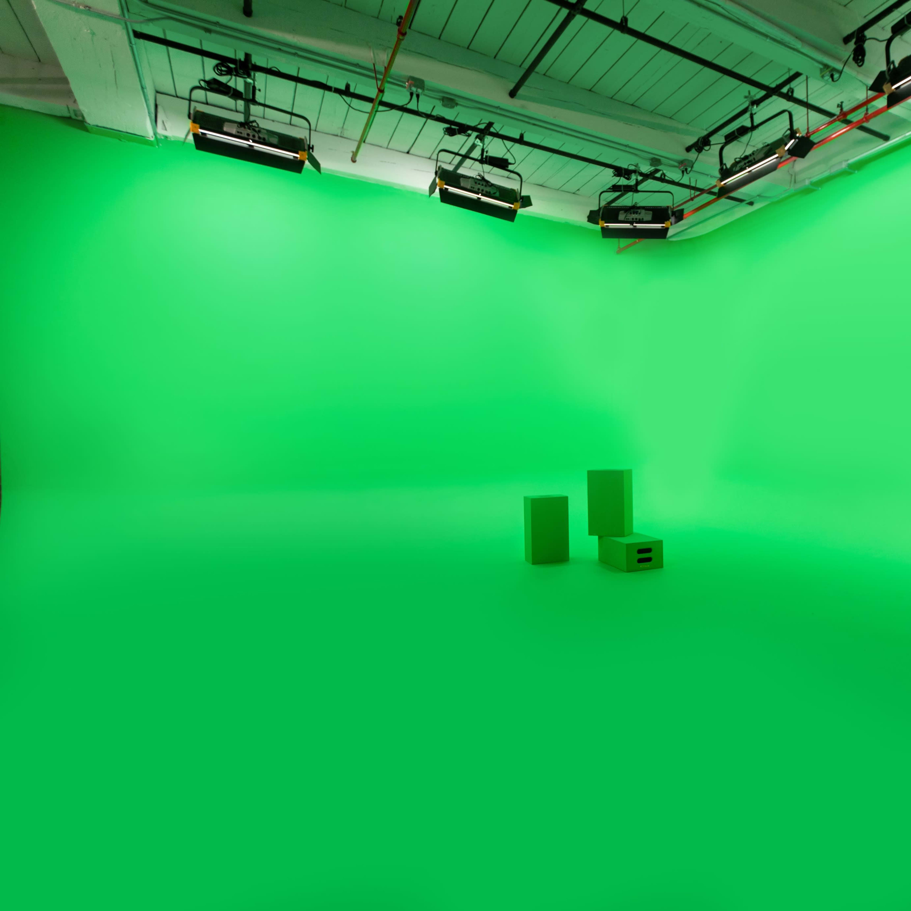 A green screen studio with two green props placed on the floor.
