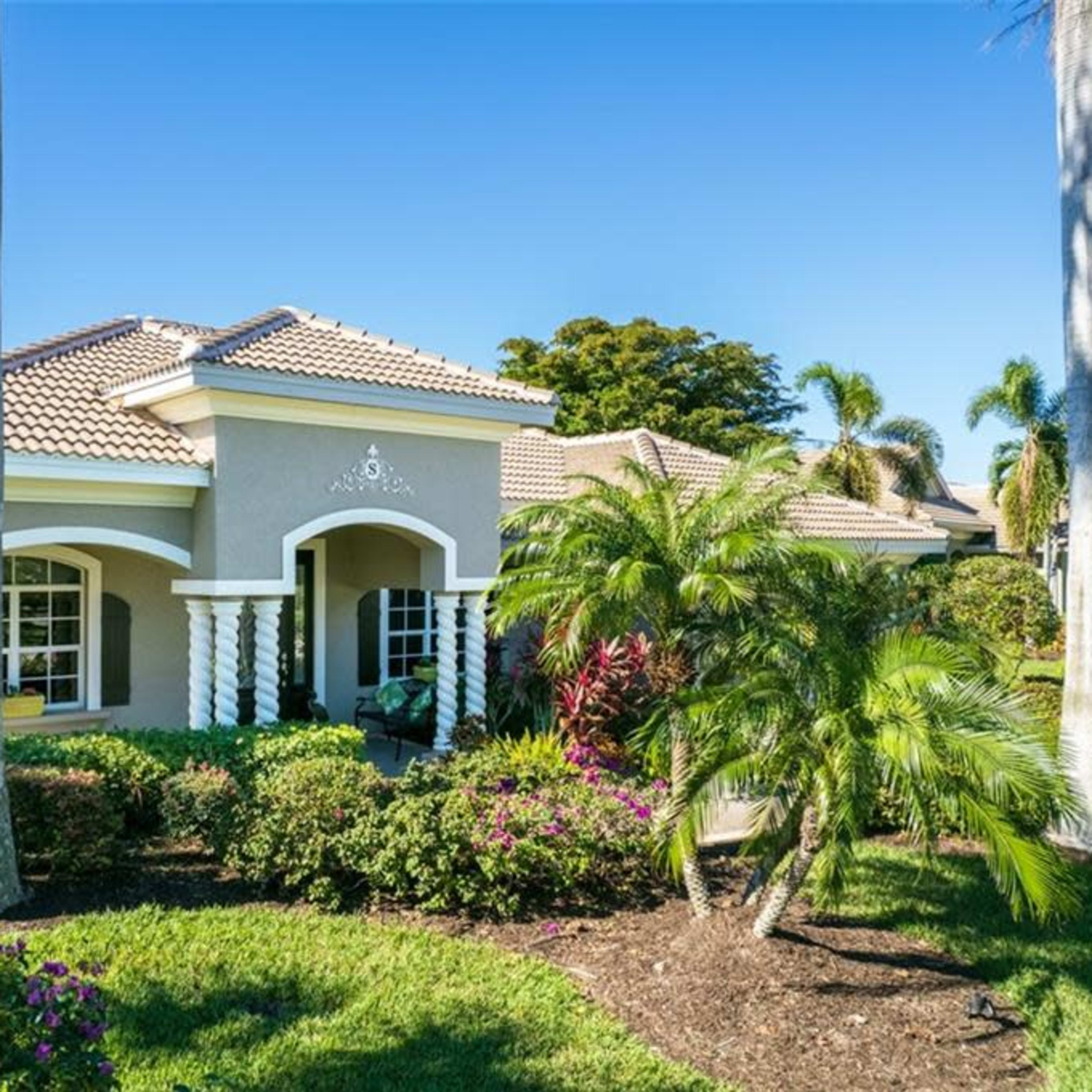 A single-story house with a tiled roof and landscaped garden is situated in a tropical setting.