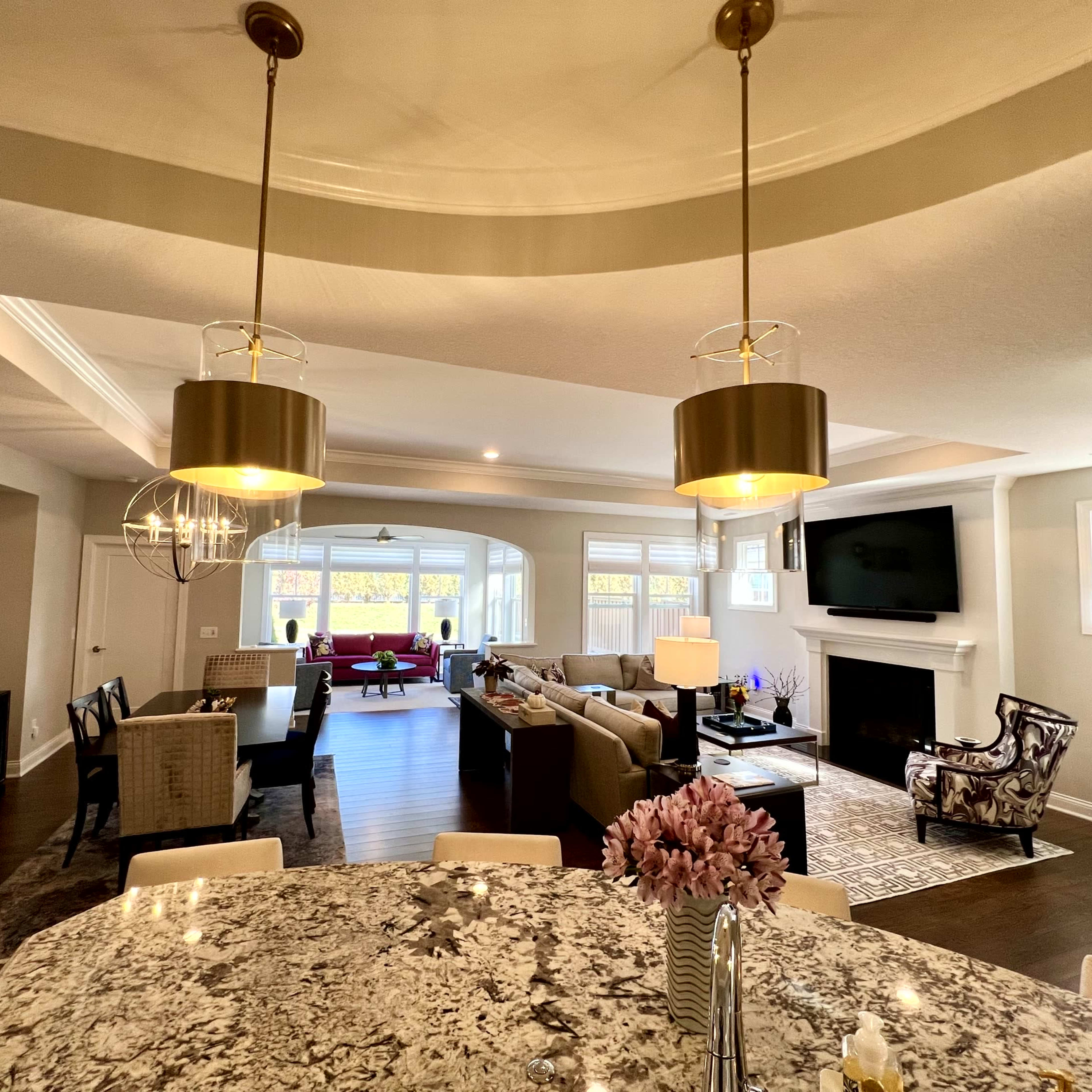 An open-concept living space featuring a kitchen with a granite counter, dining area, and a comfortable living room with large windows and a fireplace.