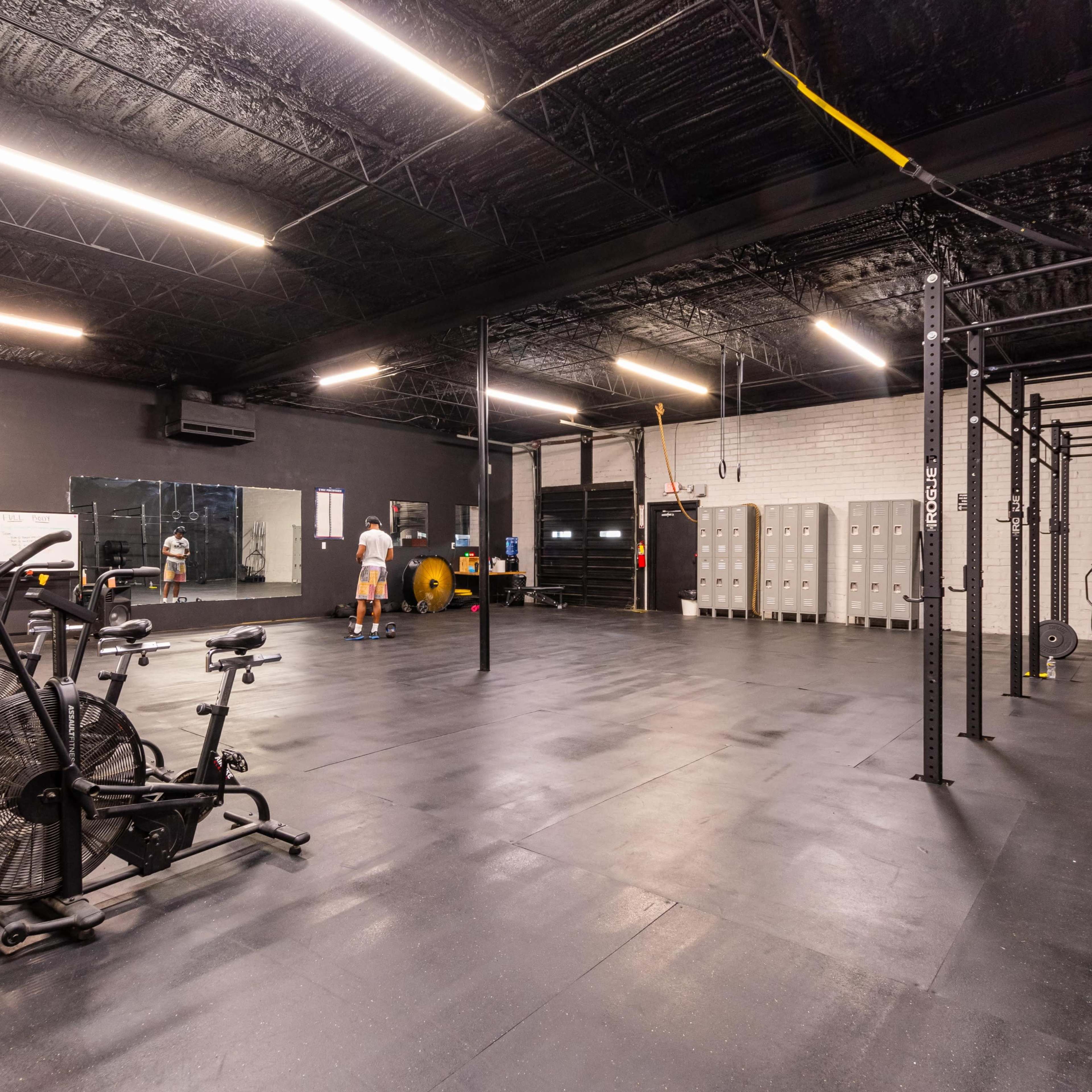 A spacious gym features exercise equipment, including stationary bikes, a weight area, and a pull-up bar, with open floor space for workouts.
