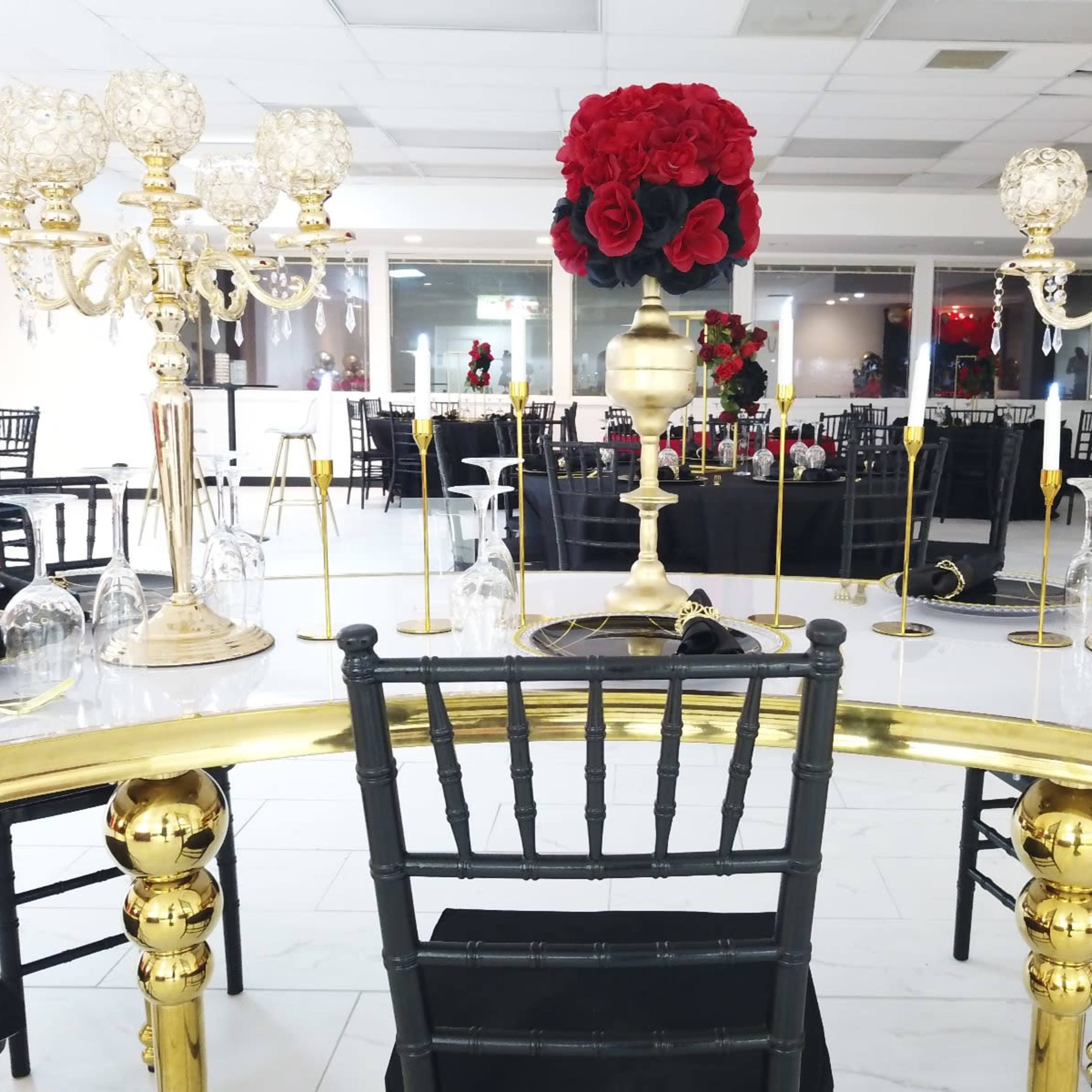 A modern dining area set up for a formal event, featuring elegantly decorated tables with black tablecloths and decorative centerpieces.
