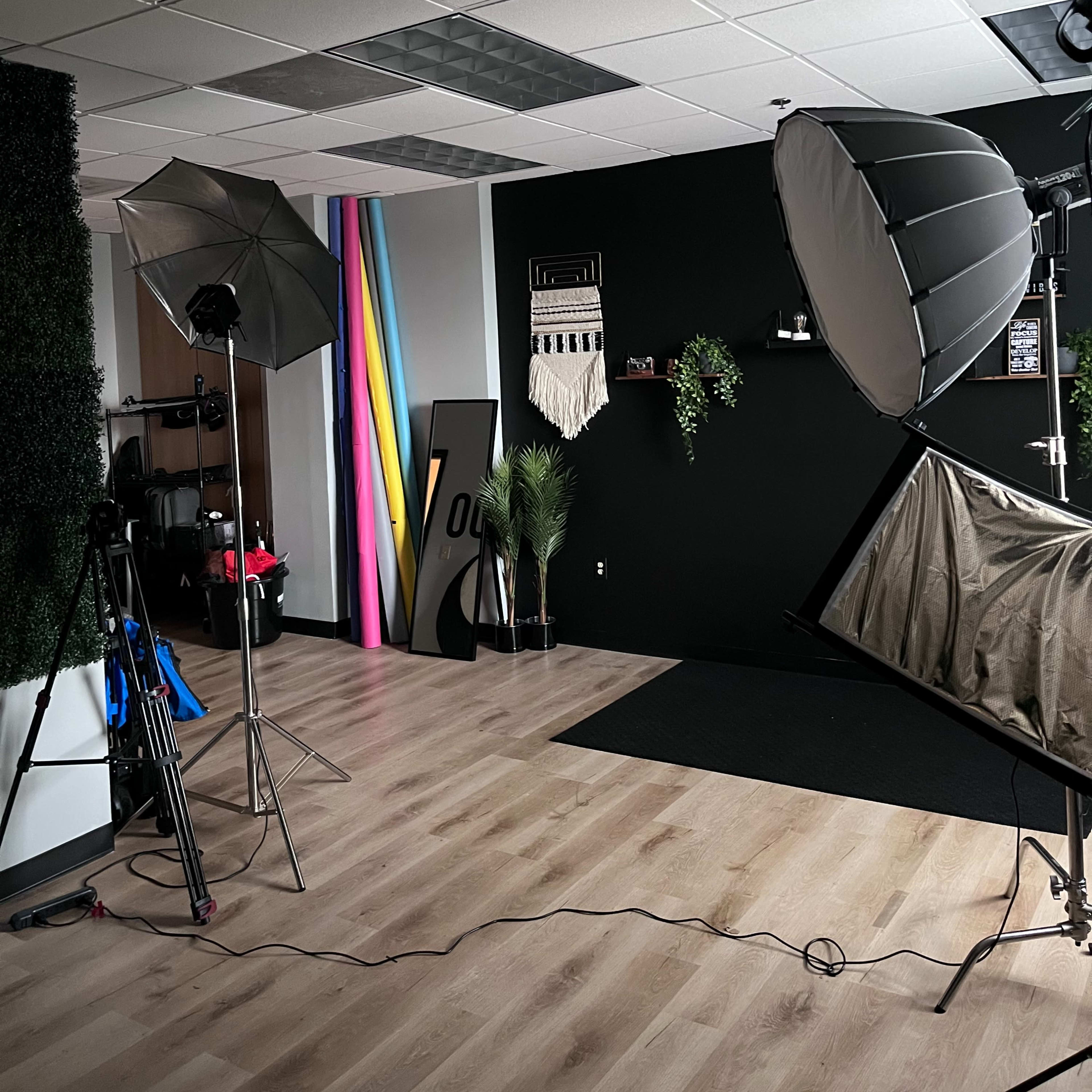 A photography studio equipped with softbox lights, multicolored backdrops, and various photography equipment arranged in a modern setting.
