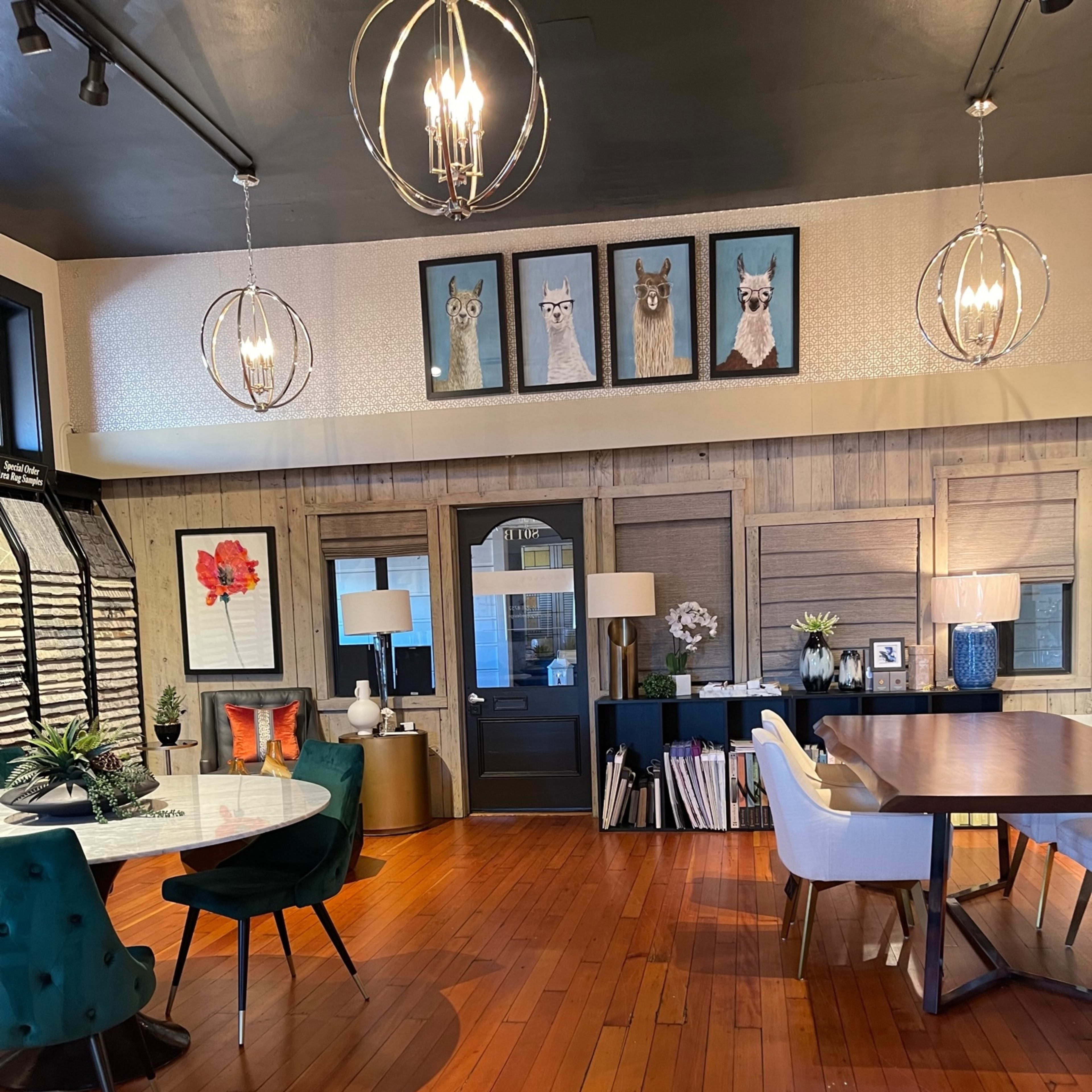 A well-decorated indoor space featuring wooden flooring, a dining table, various seating arrangements, and framed artwork of llamas on the wall.