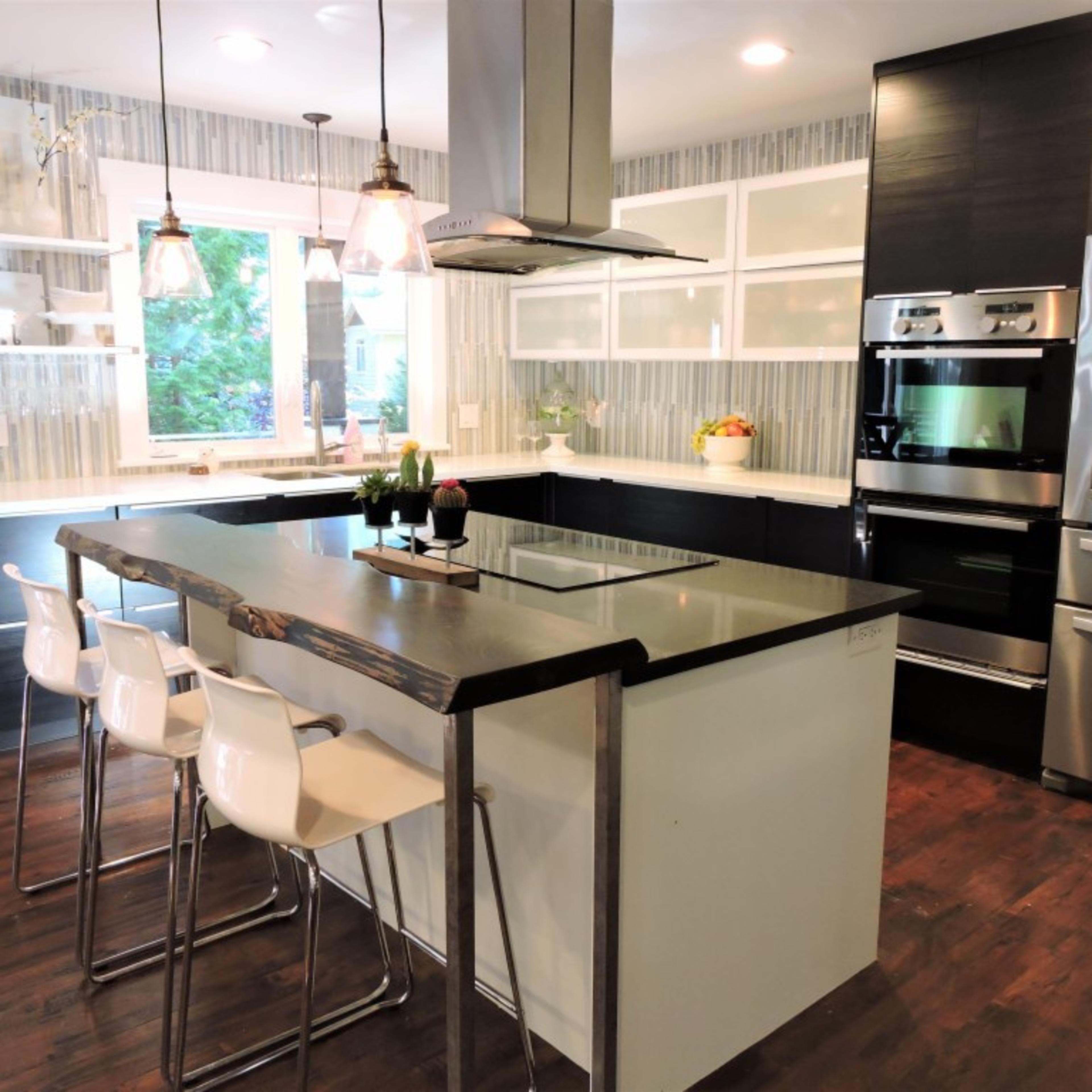 A modern kitchen features an island with seating, stainless steel appliances, and a window allowing natural light to illuminate the space.