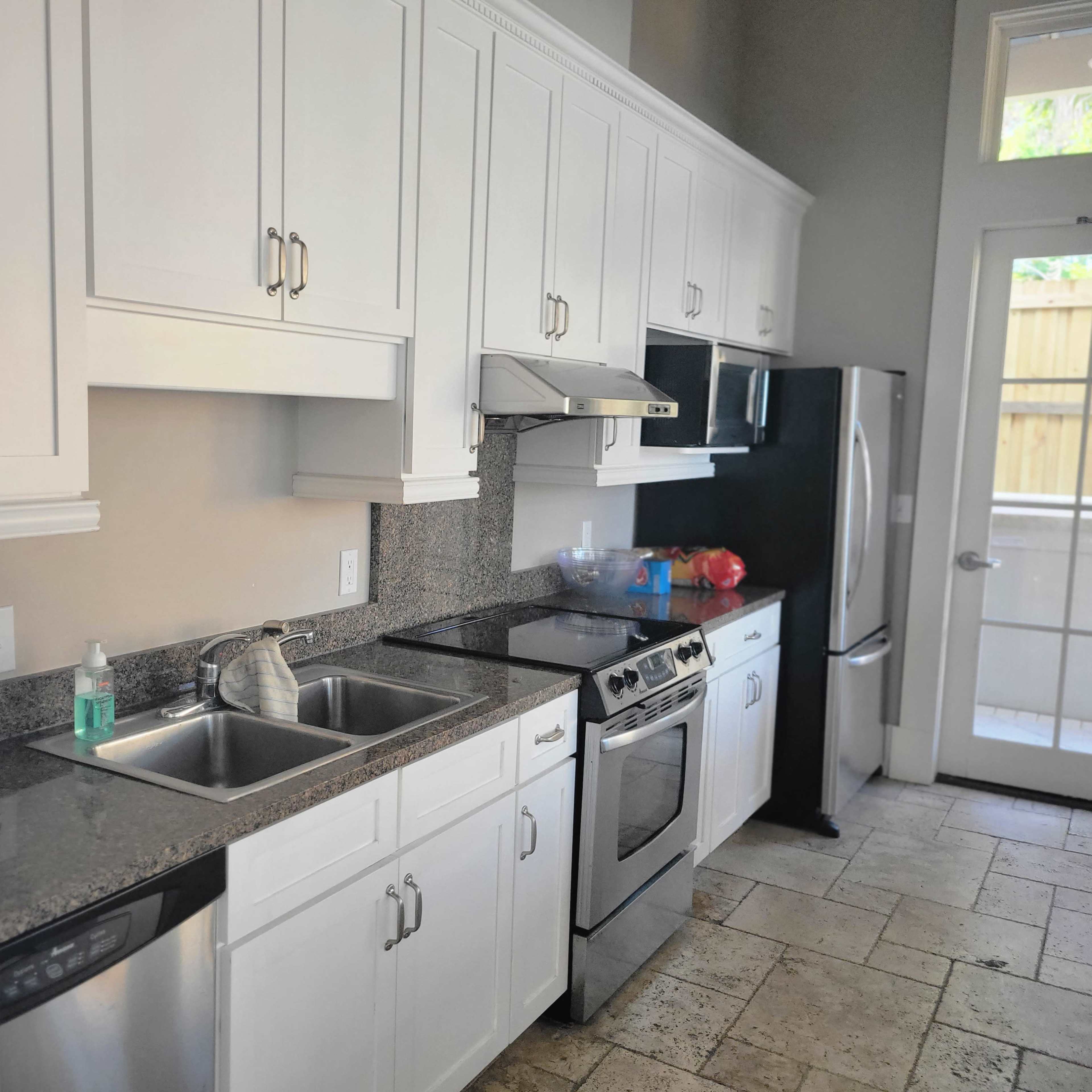 A kitchen featuring white cabinetry, stainless steel appliances, and a granite countertop.