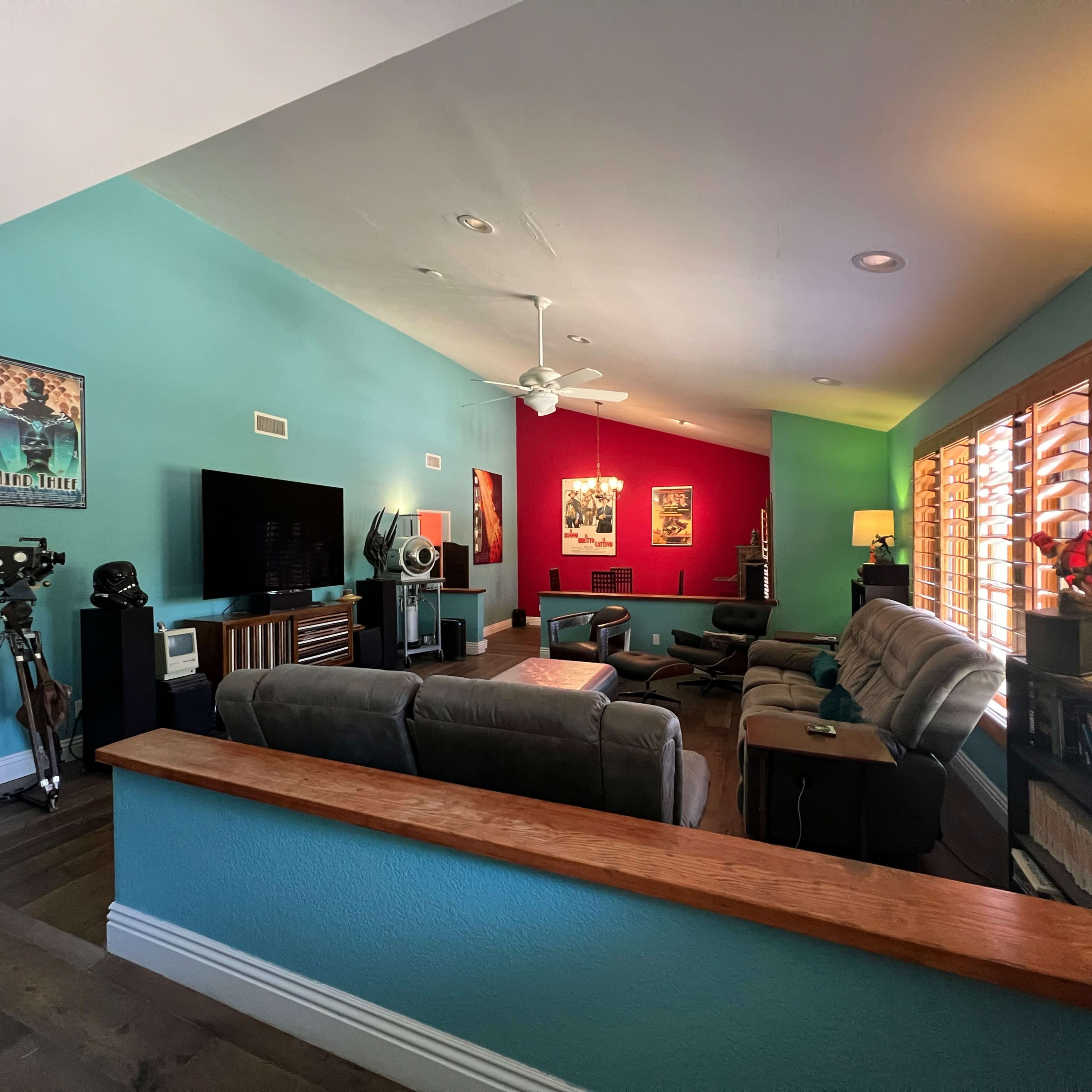 A living room with colorful walls, a television, seating arrangements, and a mix of decor, including a camera tripod and framed art.