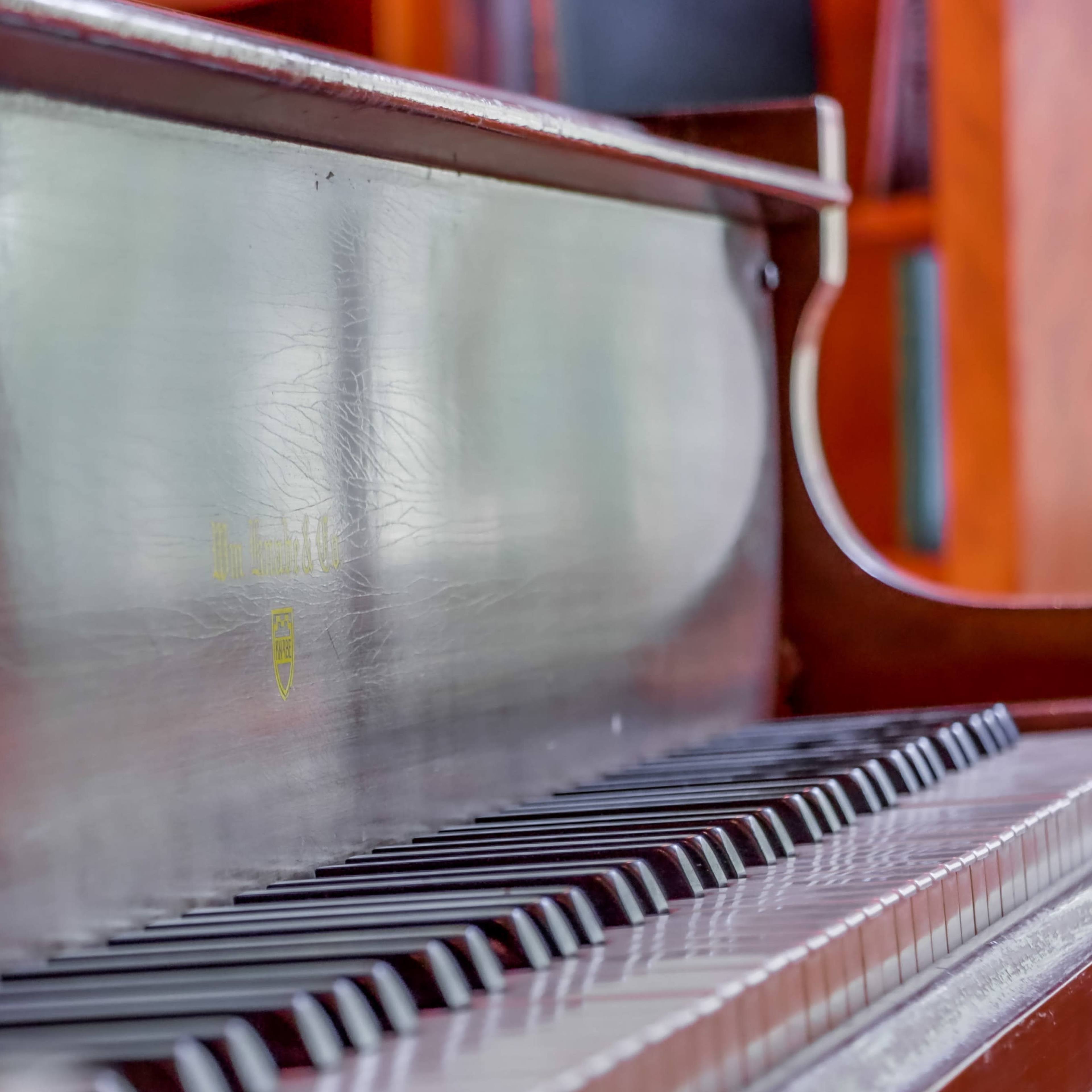 A close-up view of a piano keyboard with wooden finish and visible keys.