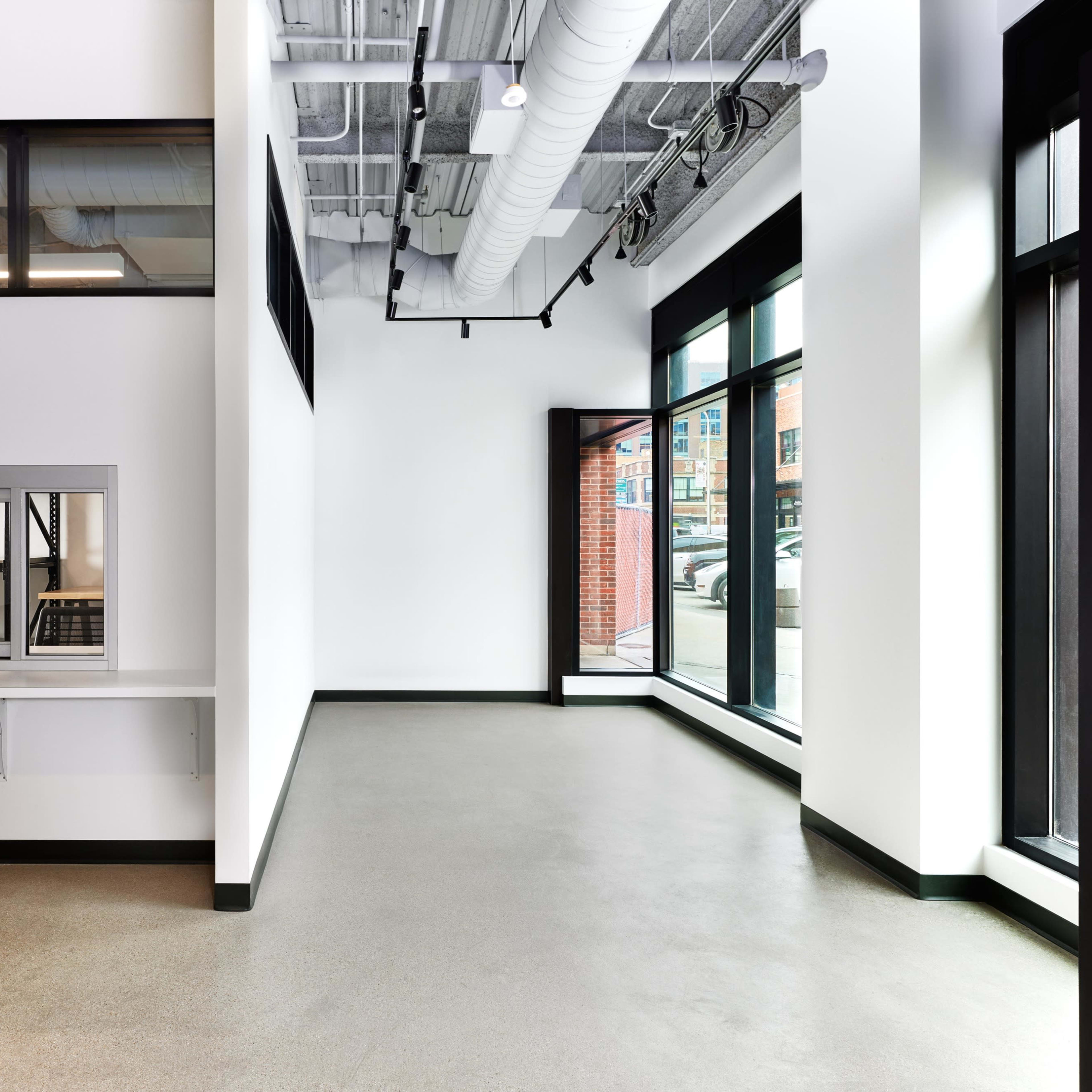 An empty, modern interior space with large windows and minimal furnishings.