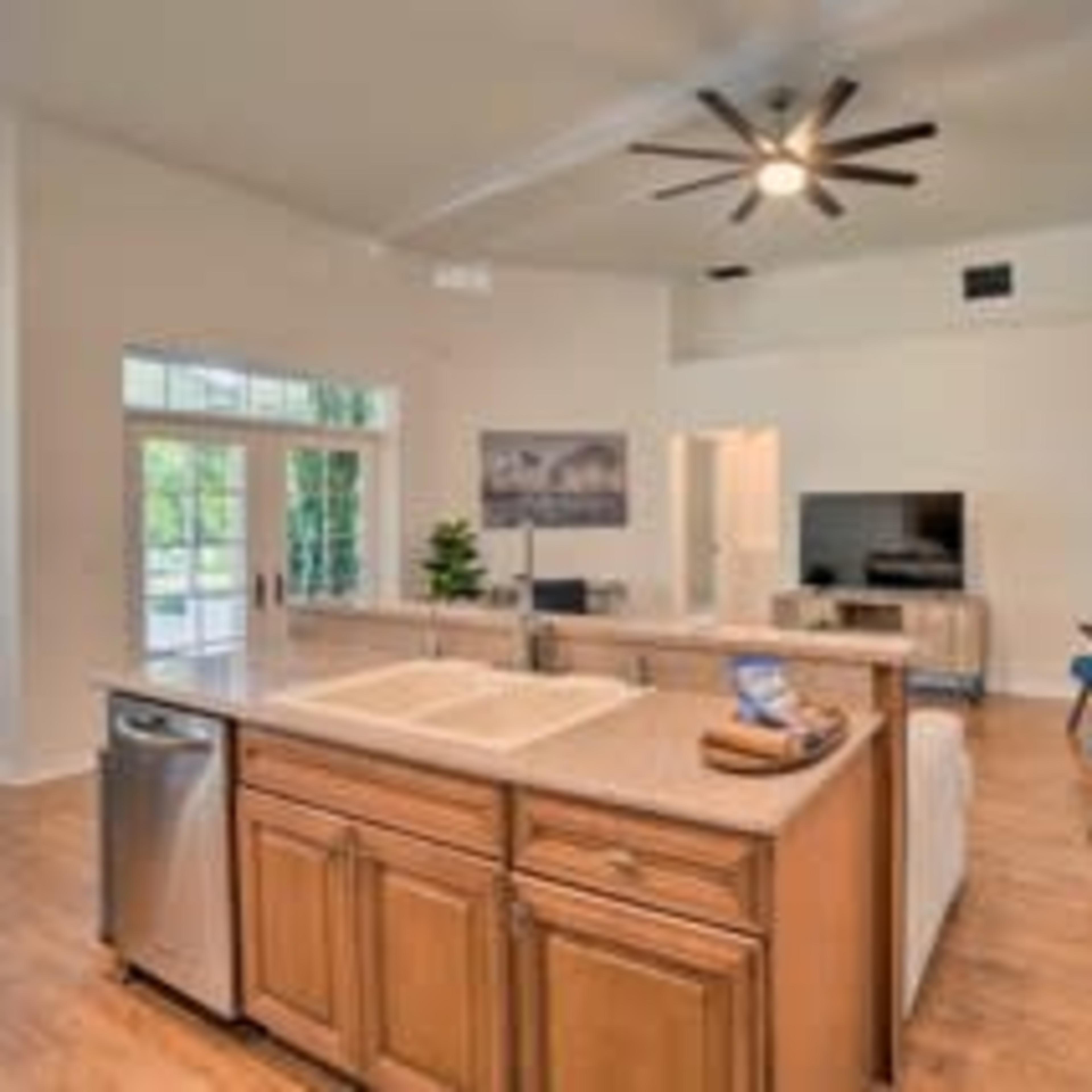 A spacious kitchen and living area with an island, modern appliances, and large windows allowing natural light to enter.