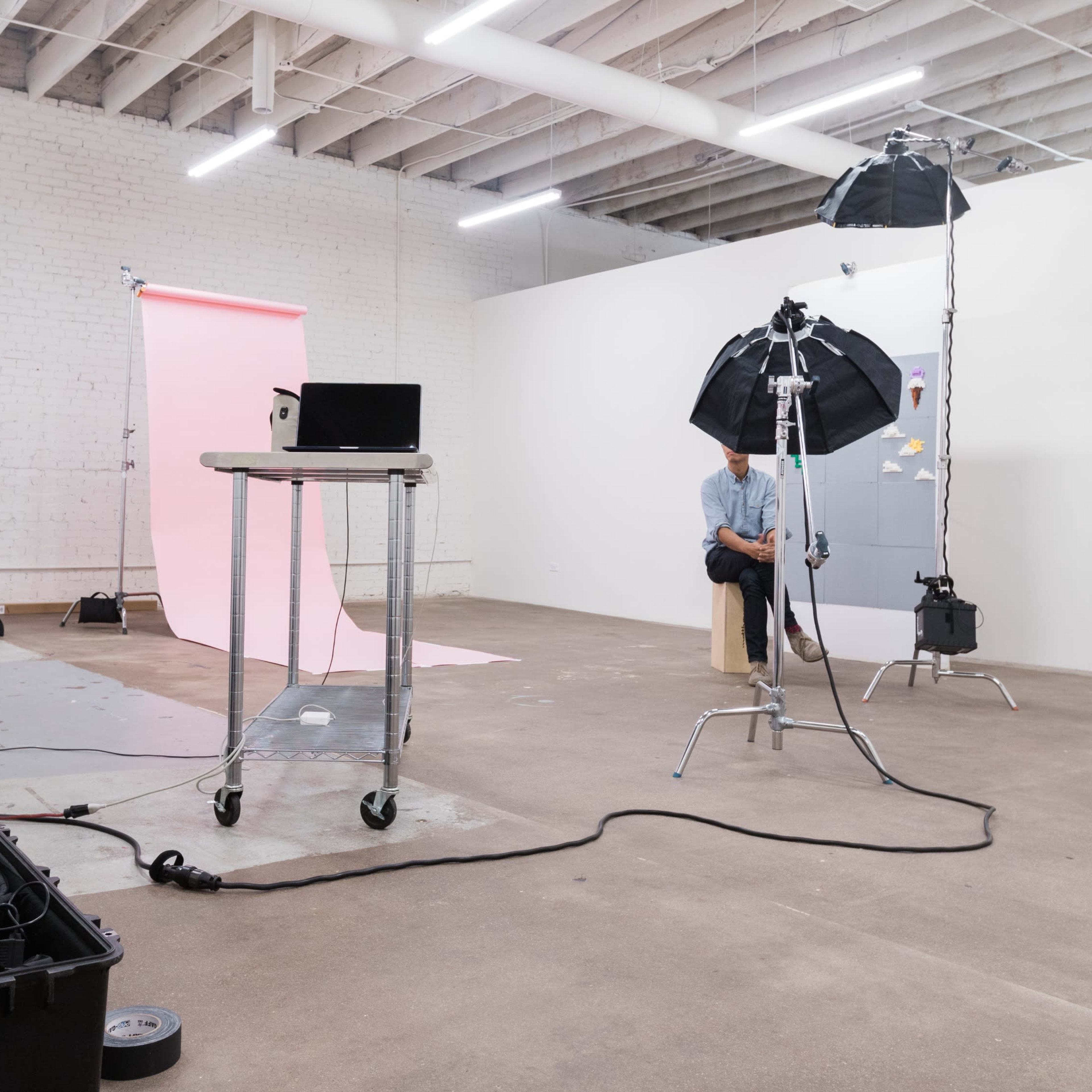 A photographer captures a subject in a studio setting equipped with multiple light stands and a backdrop.