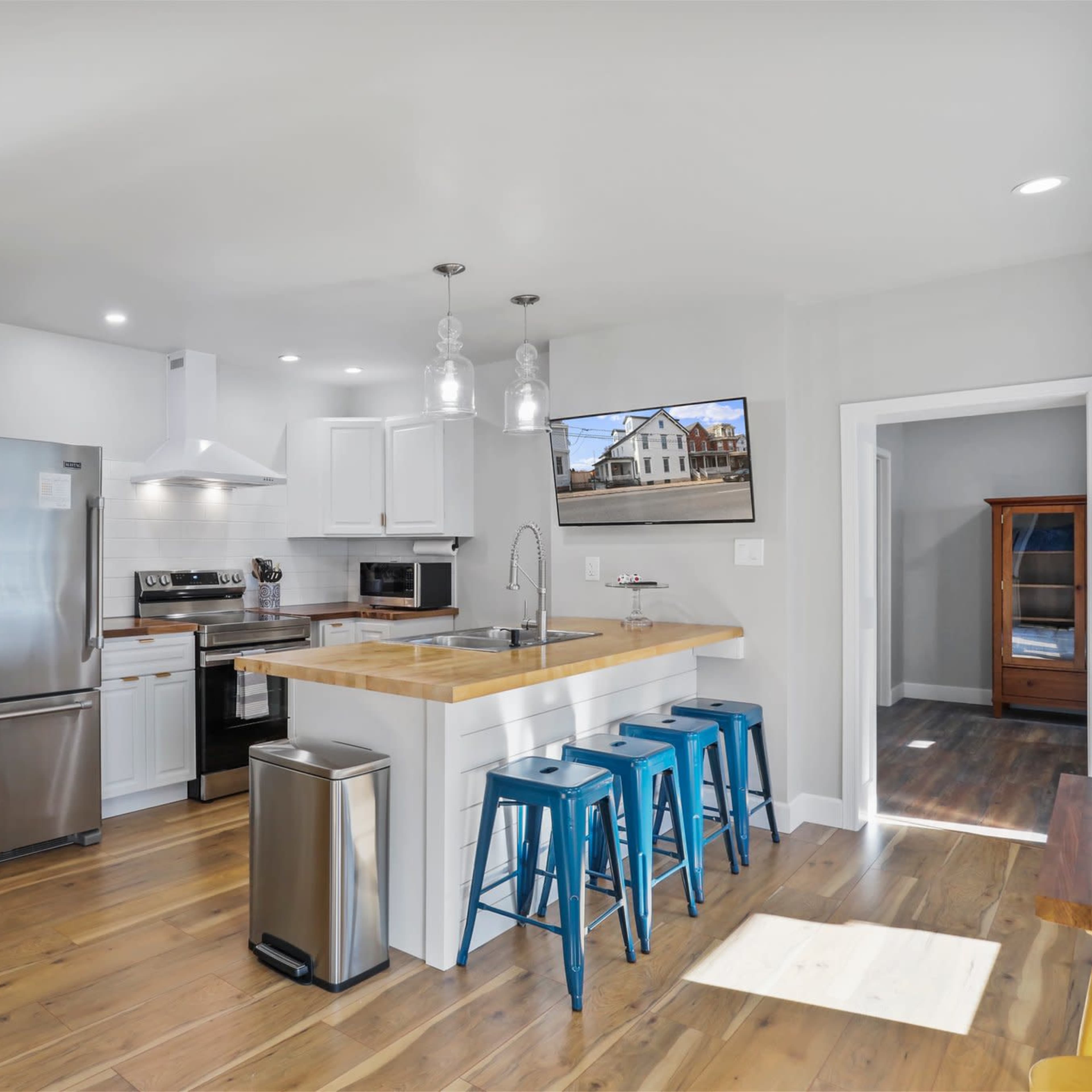 A modern kitchen with a large island, stainless steel appliances, and light wood flooring.