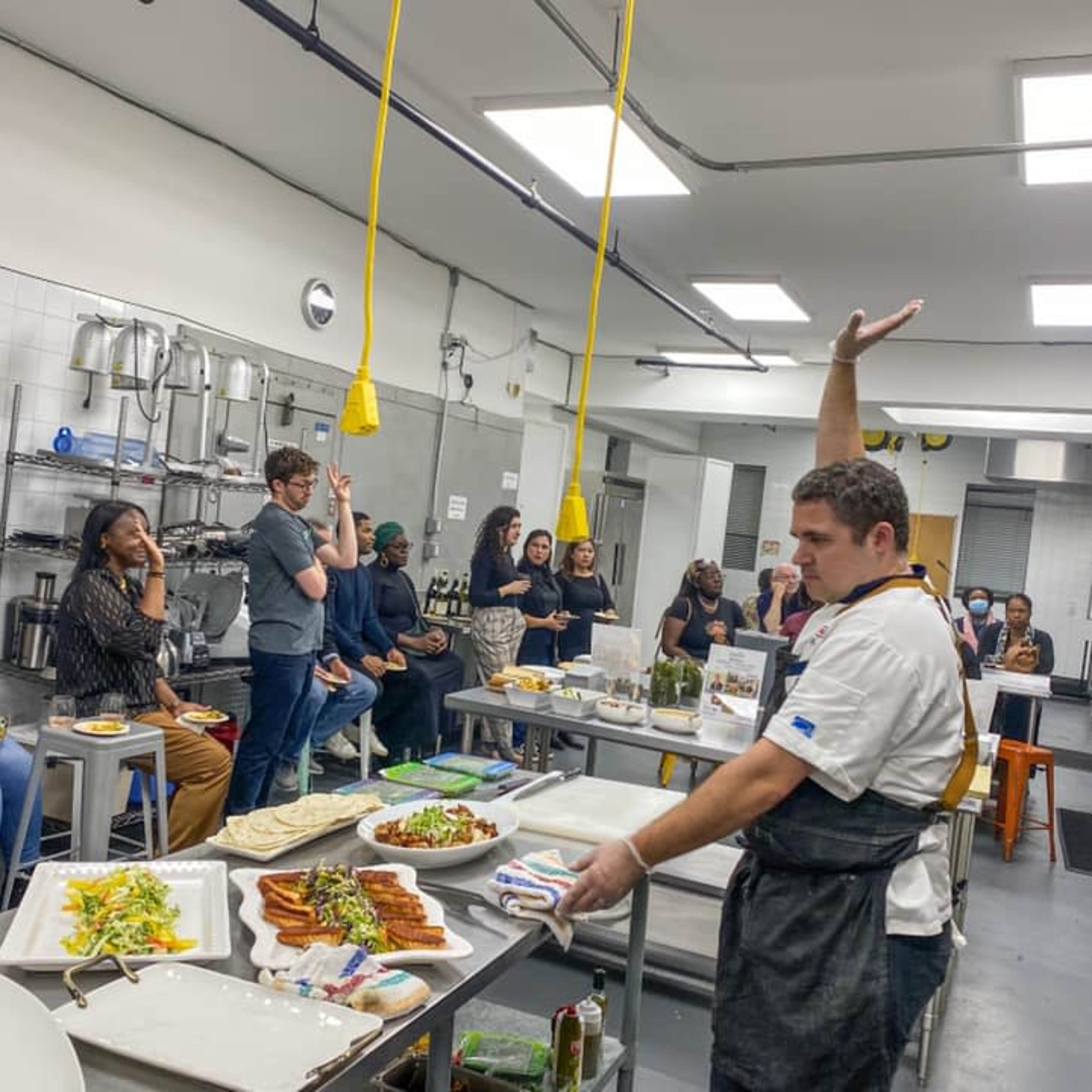 A spacious commercial kitchen equipped with stainless steel tables, metal stools, and industrial appliances.
