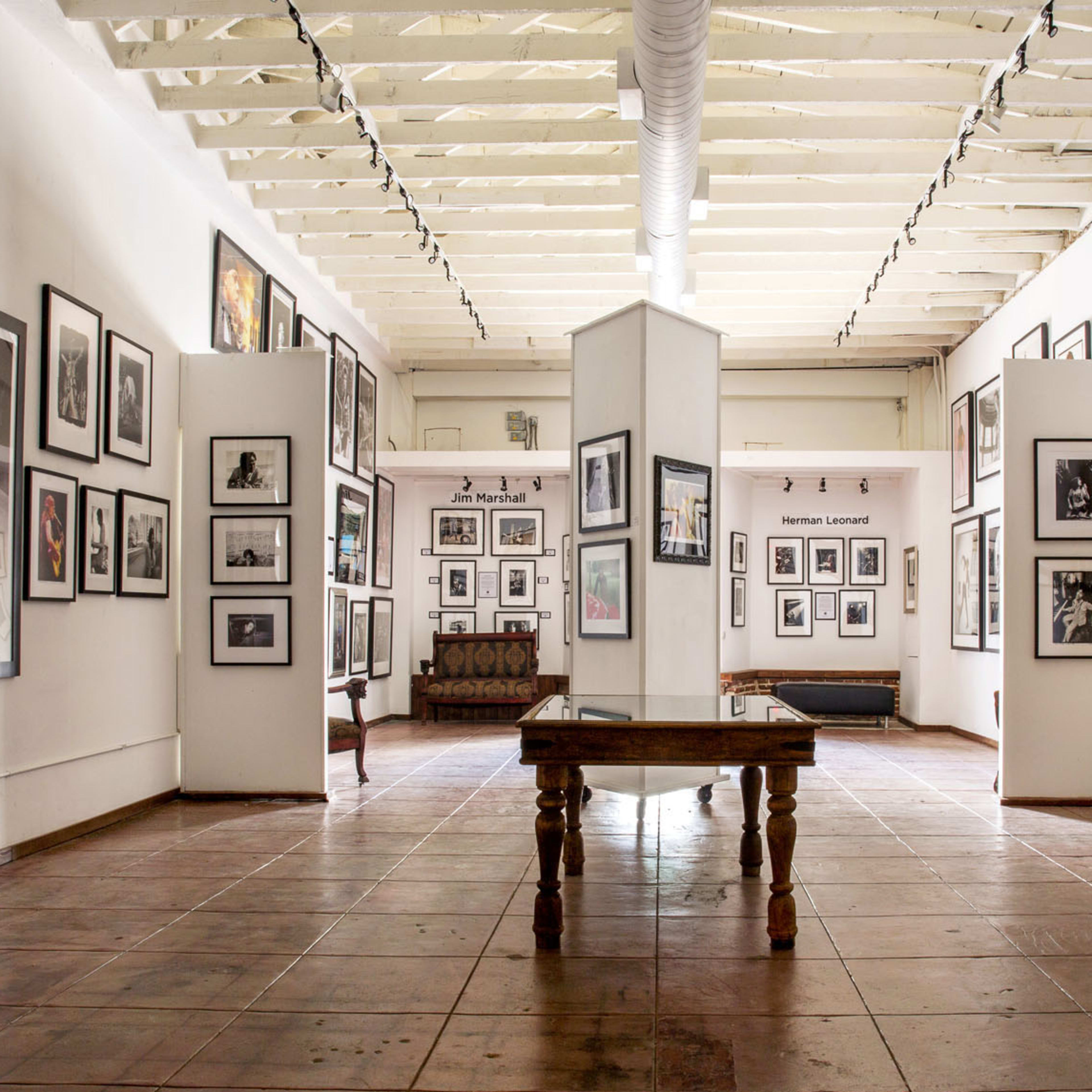 An art gallery with framed photographs displayed on the walls and a wooden table in the center.