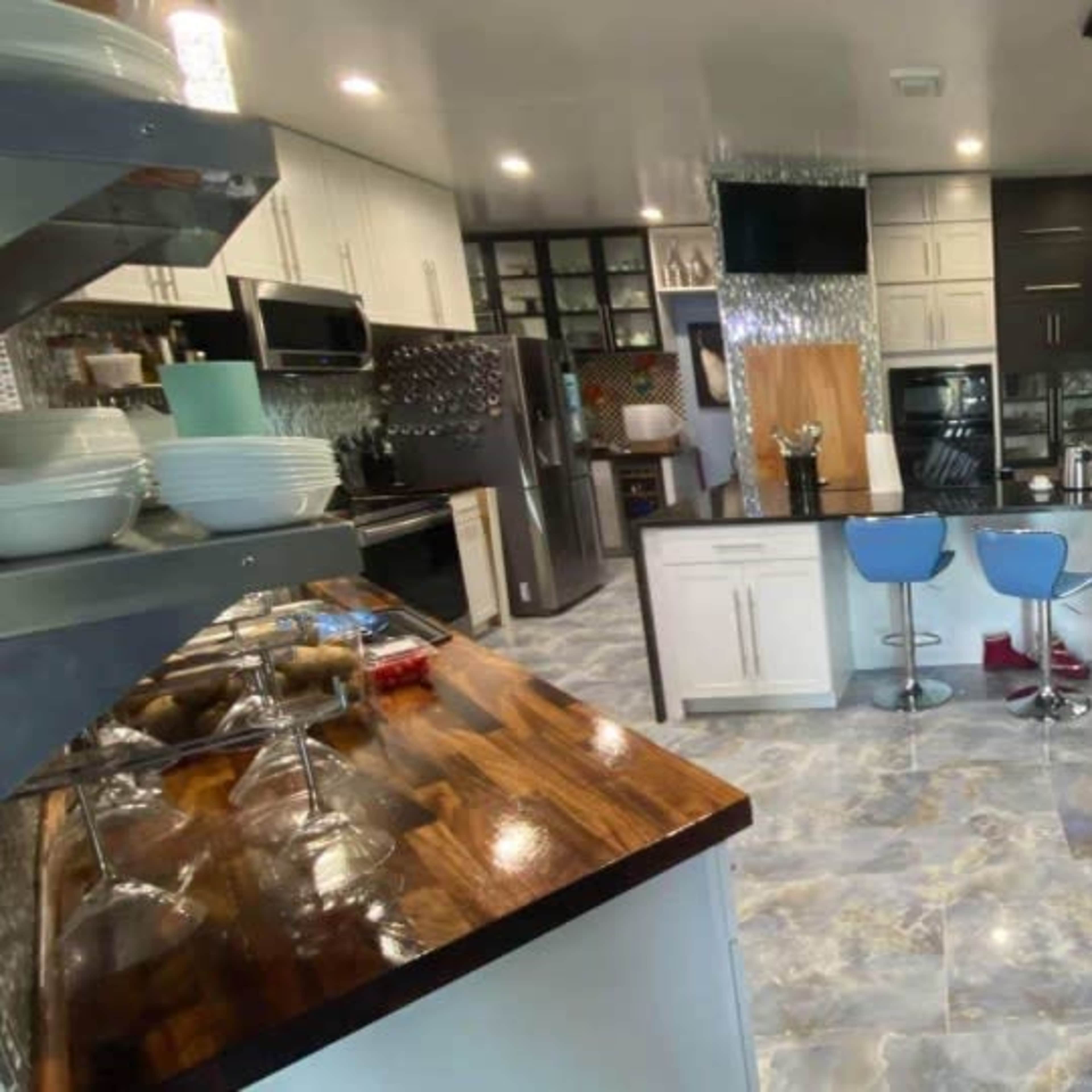 A modern kitchen with a combination of dark and light cabinetry, stainless steel appliances, and a central island with bar seating.