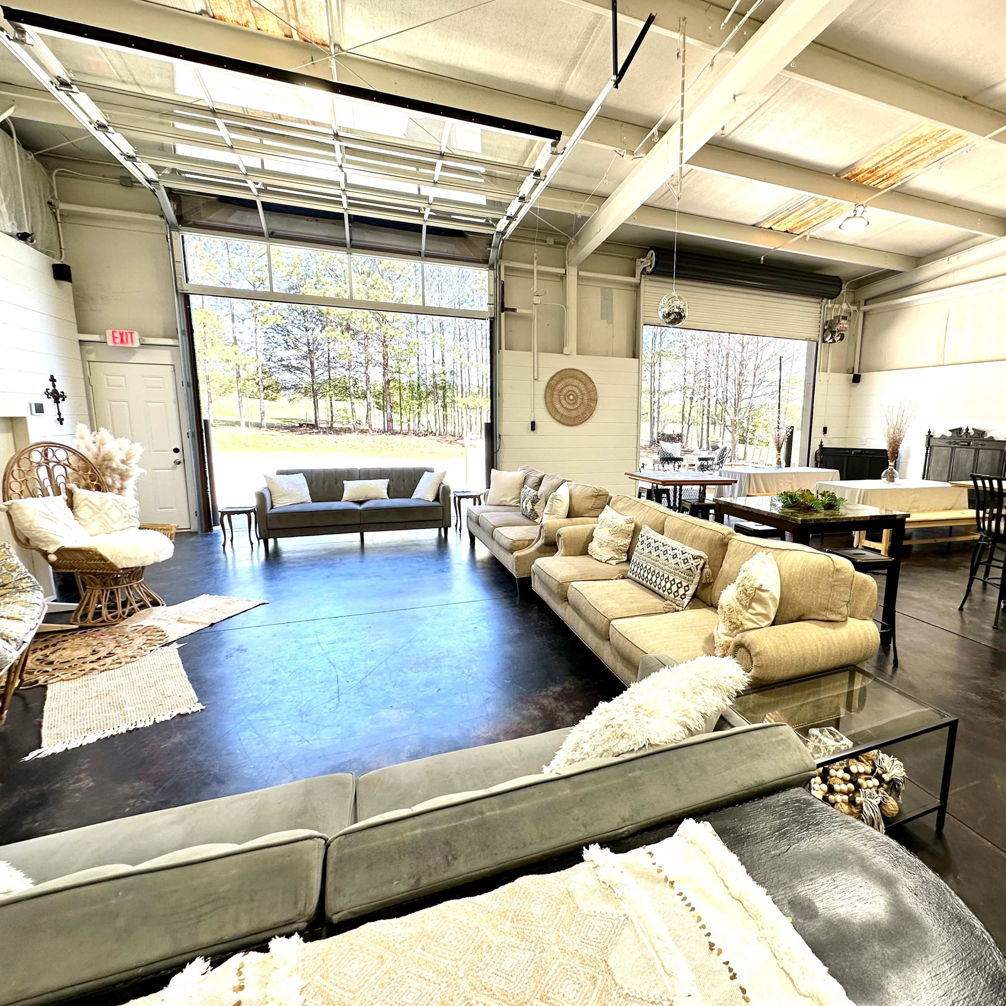 A spacious interior with a modern design featuring multiple seating areas, a dining table, and large windows allowing natural light to enter.