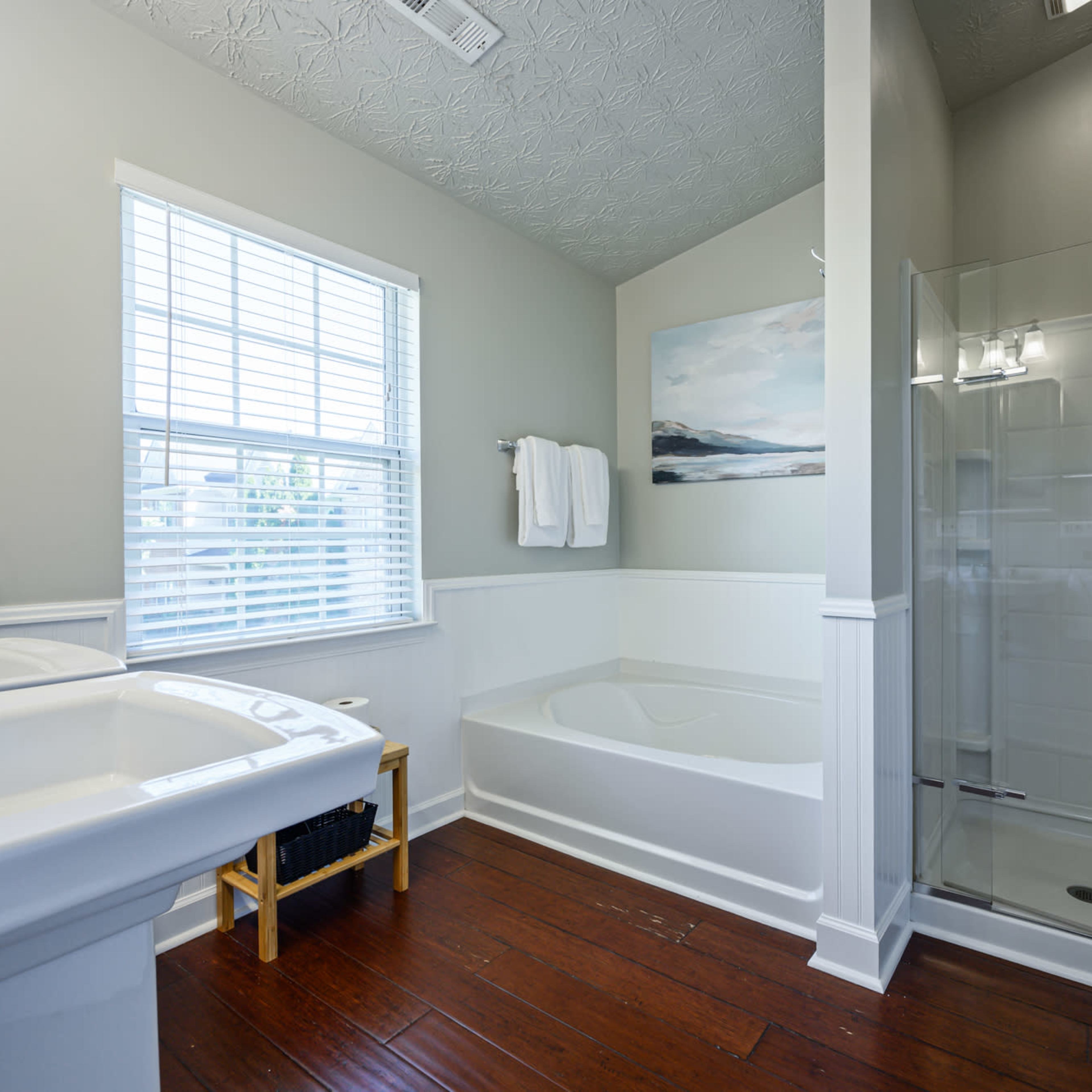 The bathroom features a soaking tub, a separate shower, a window with blinds, and a vanity with a sink.