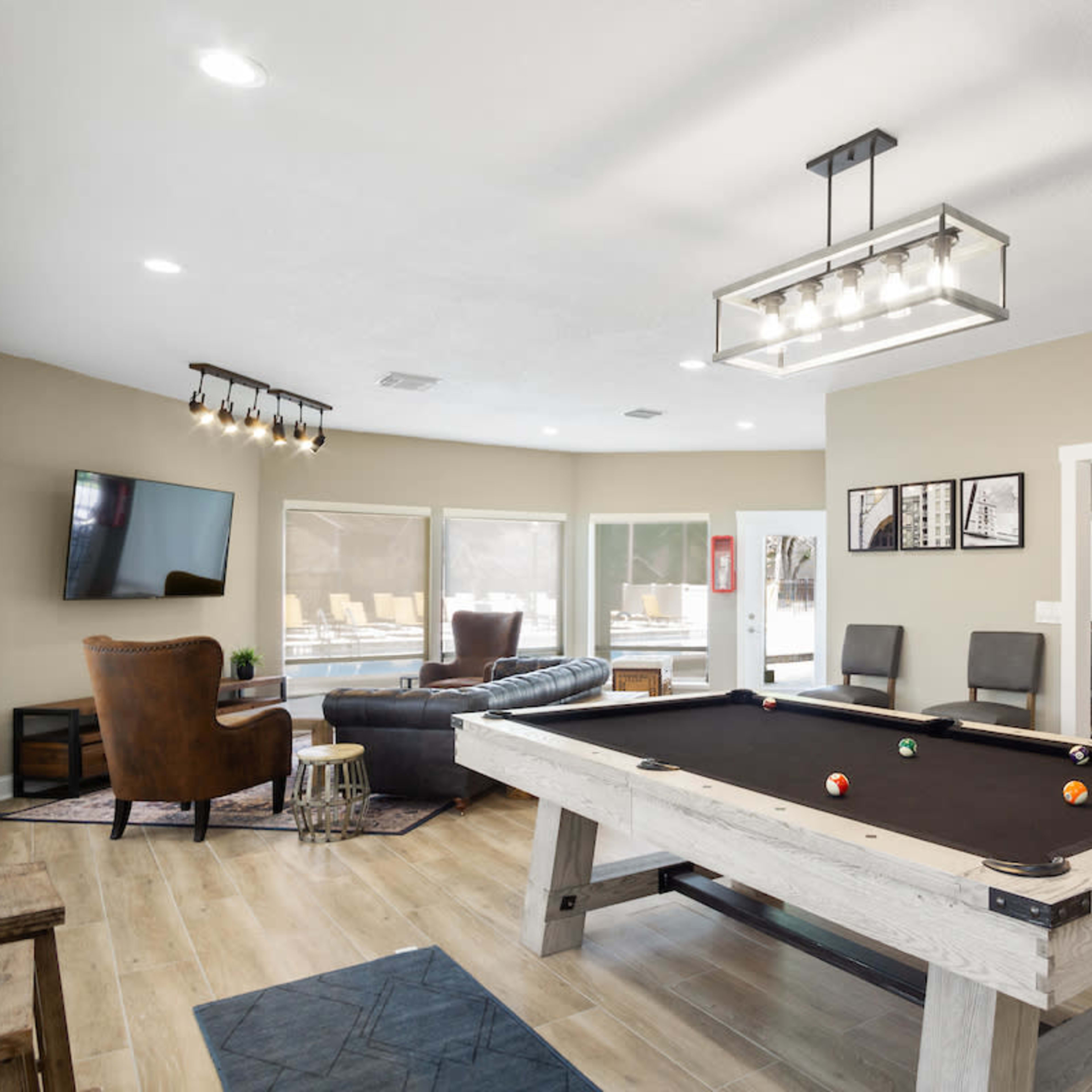 A spacious living area featuring a pool table, a sectional sofa, a television, and a dining area in an open floor plan.