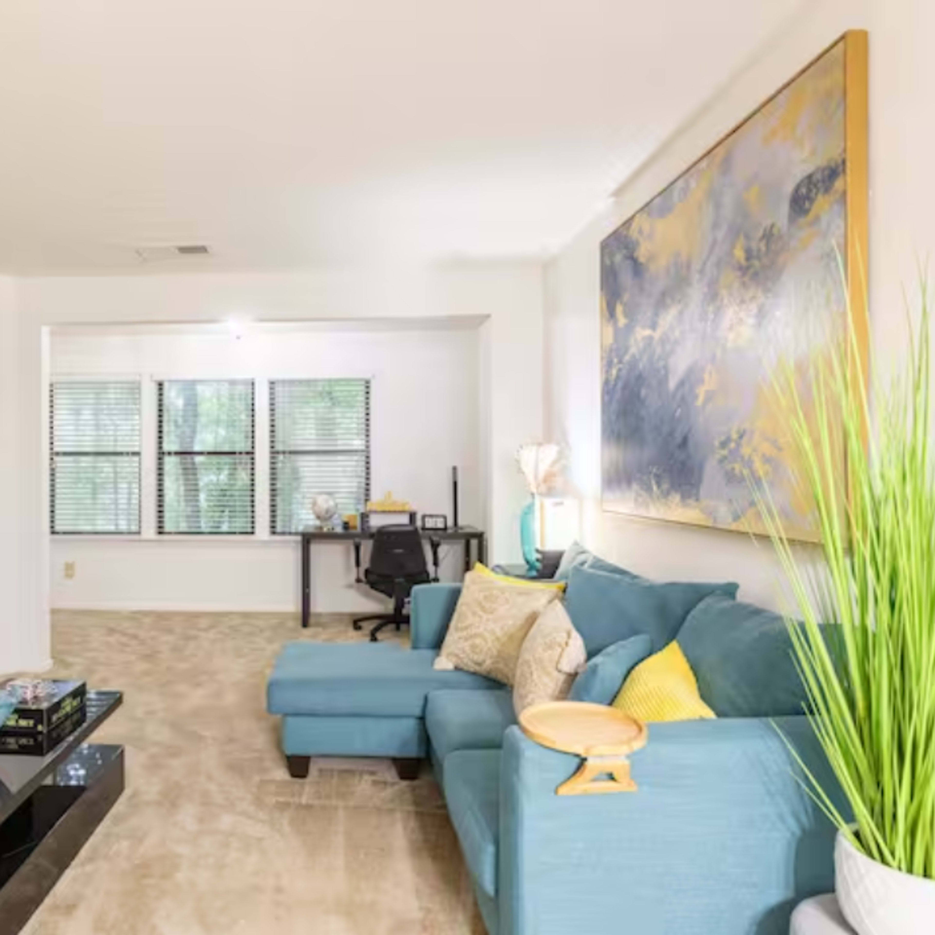 A living room with a turquoise couch, a black coffee table, a fireplace, and a wall-mounted TV.