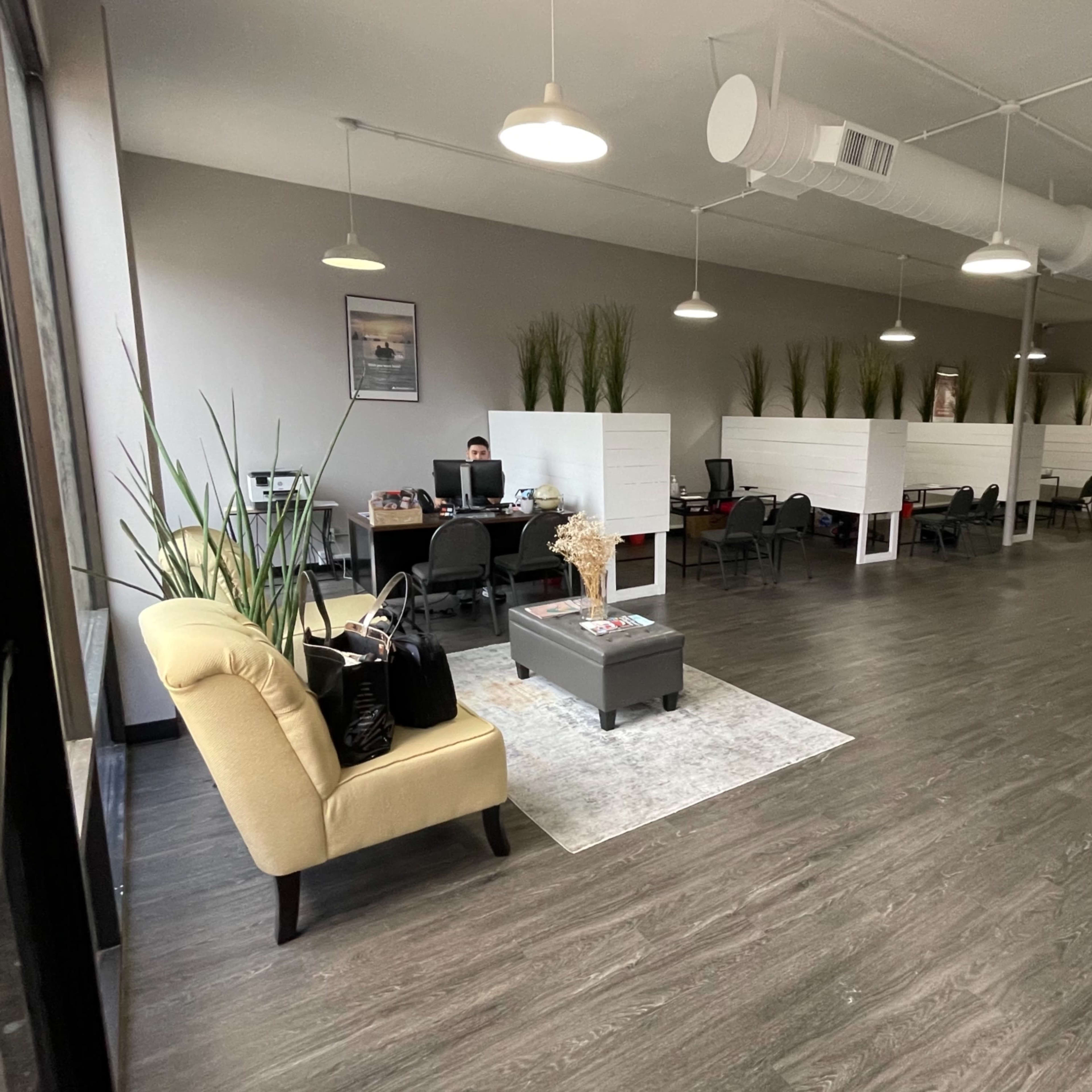 A modern office space with cubicles, a seating area, and decorative plants.