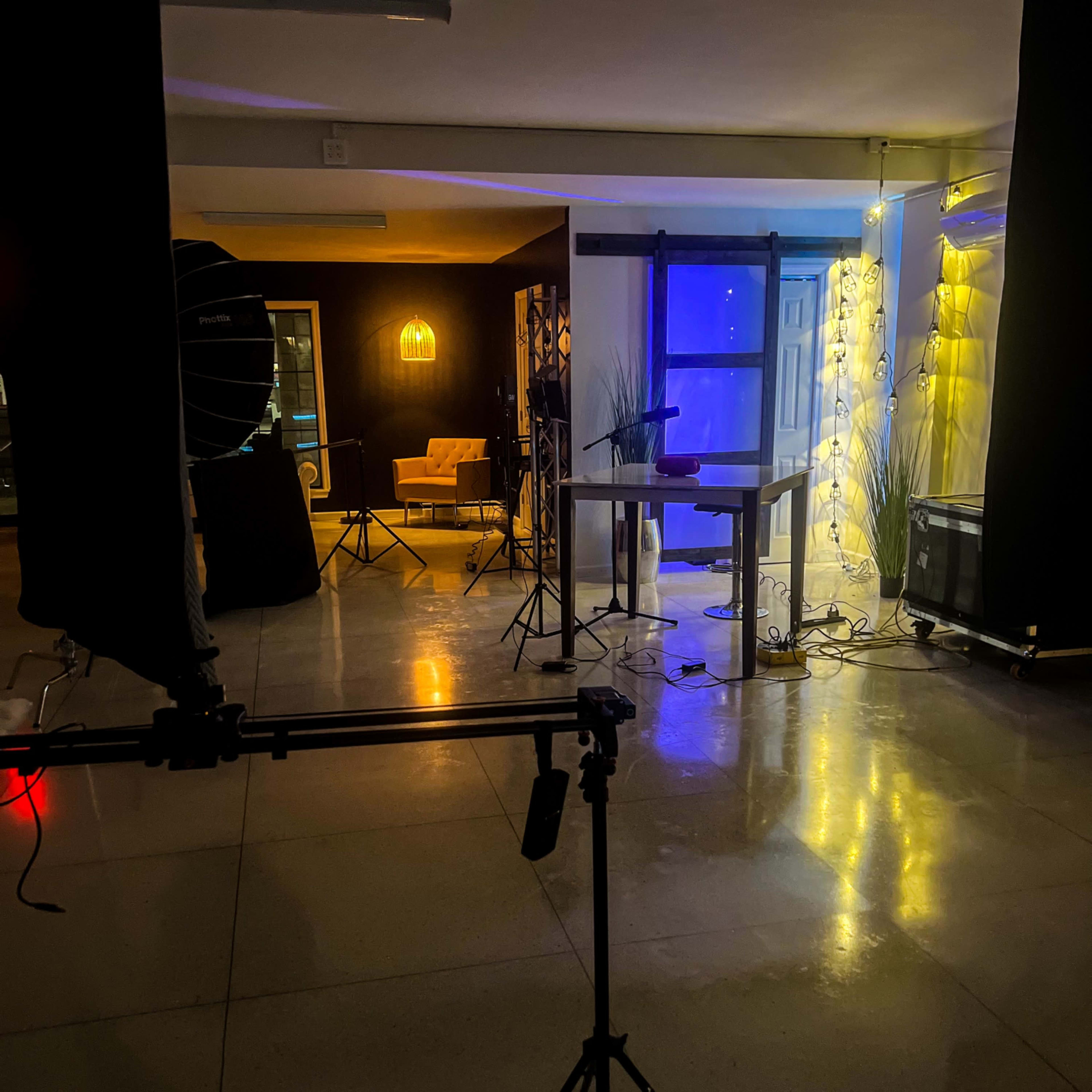 A dimly lit studio space featuring various lighting equipment and a backdrop.