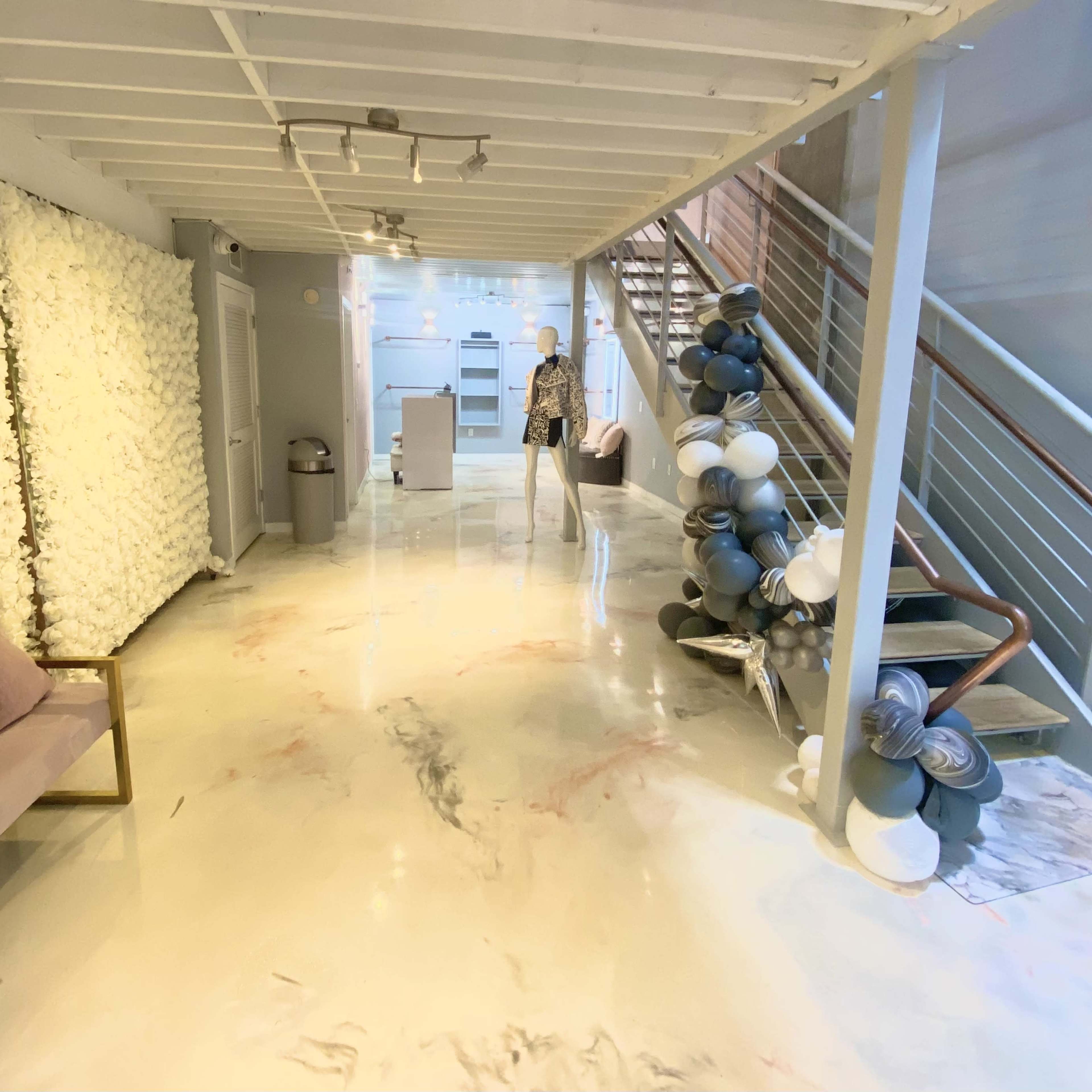 A modern interior space featuring a staircase, a mannequin on display, a seating area, and a decorative wall with white textures.