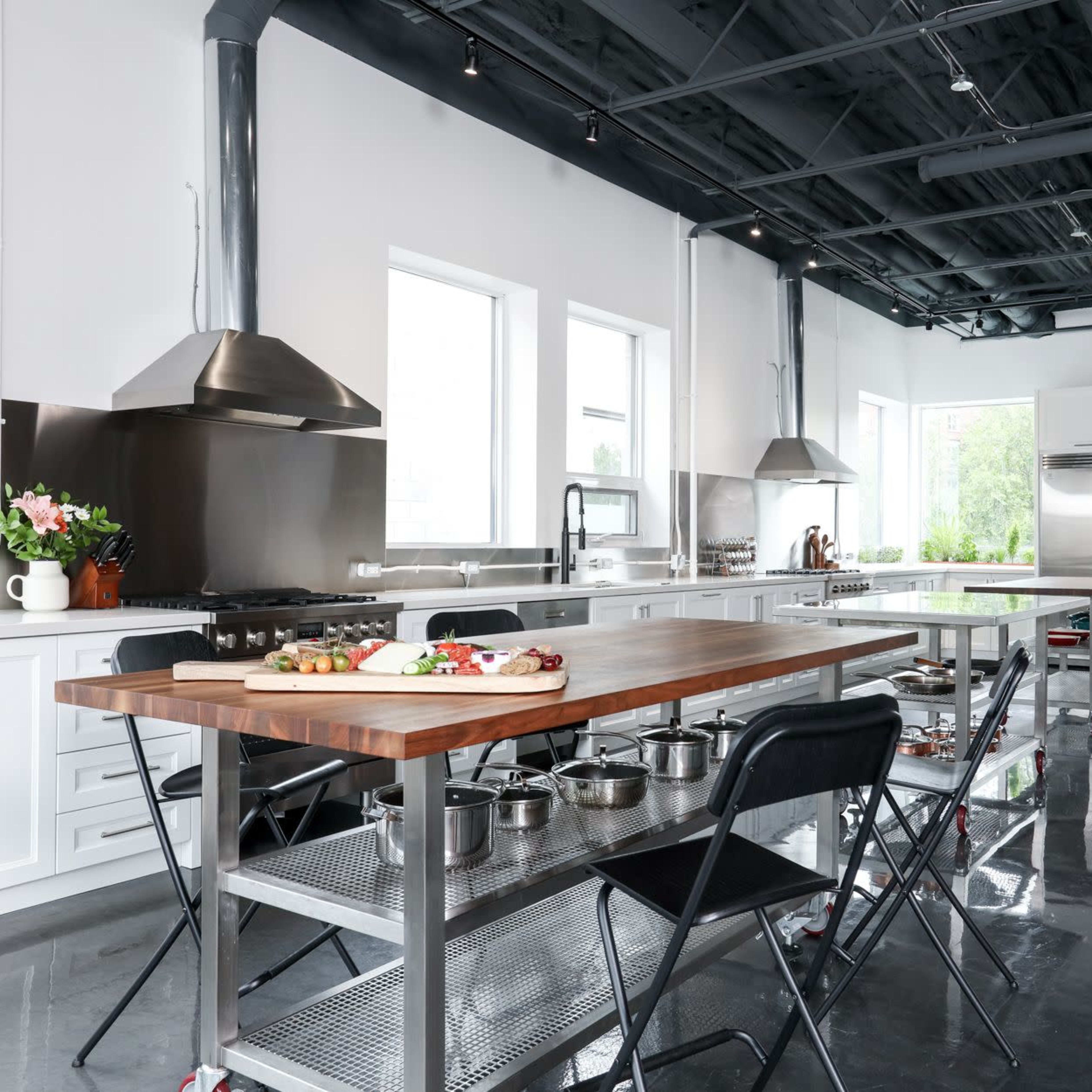 A modern kitchen with stainless steel appliances, a large wooden island, and sleek cabinetry.