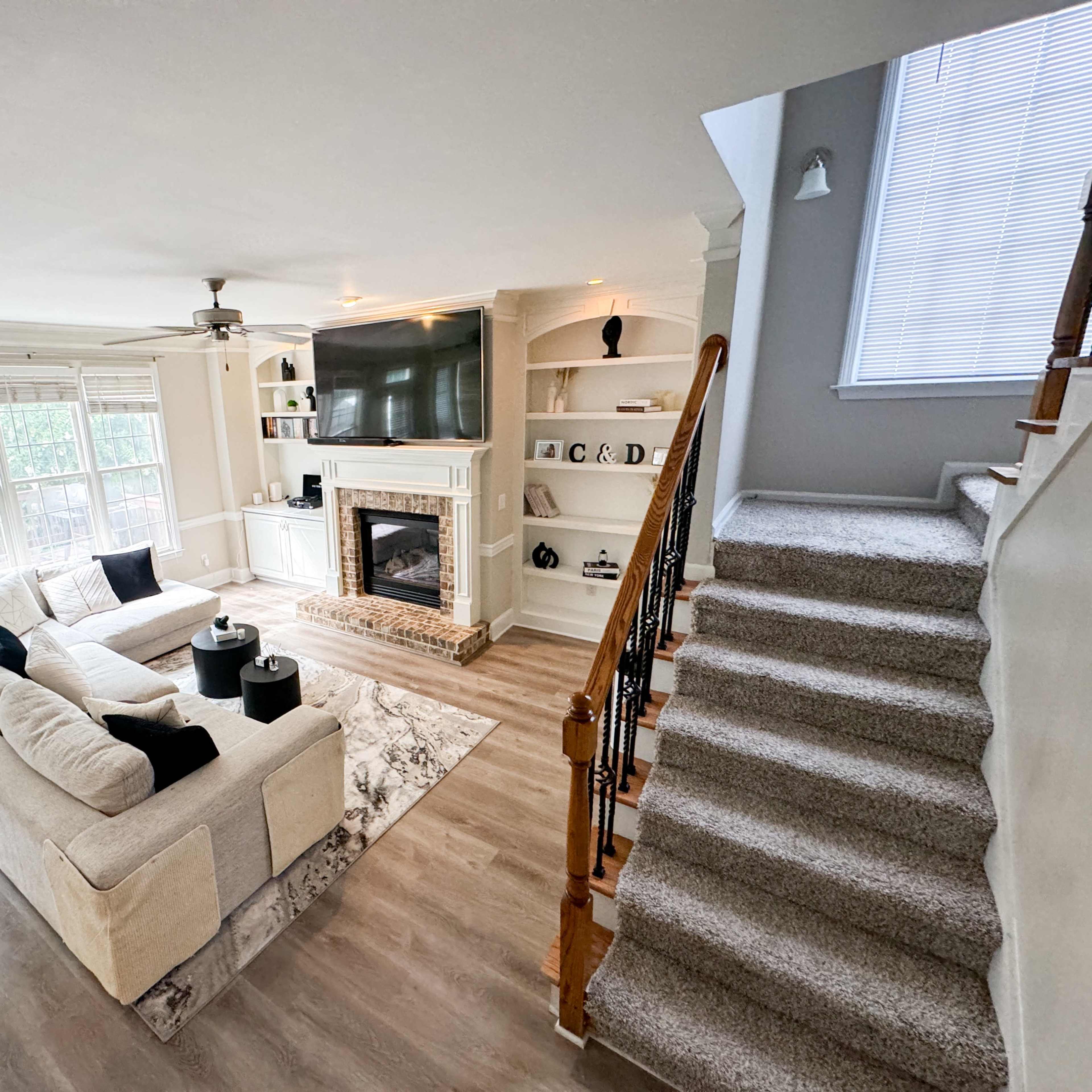 A spacious living room with a large sectional sofa, a fireplace, and a staircase leading to another level.