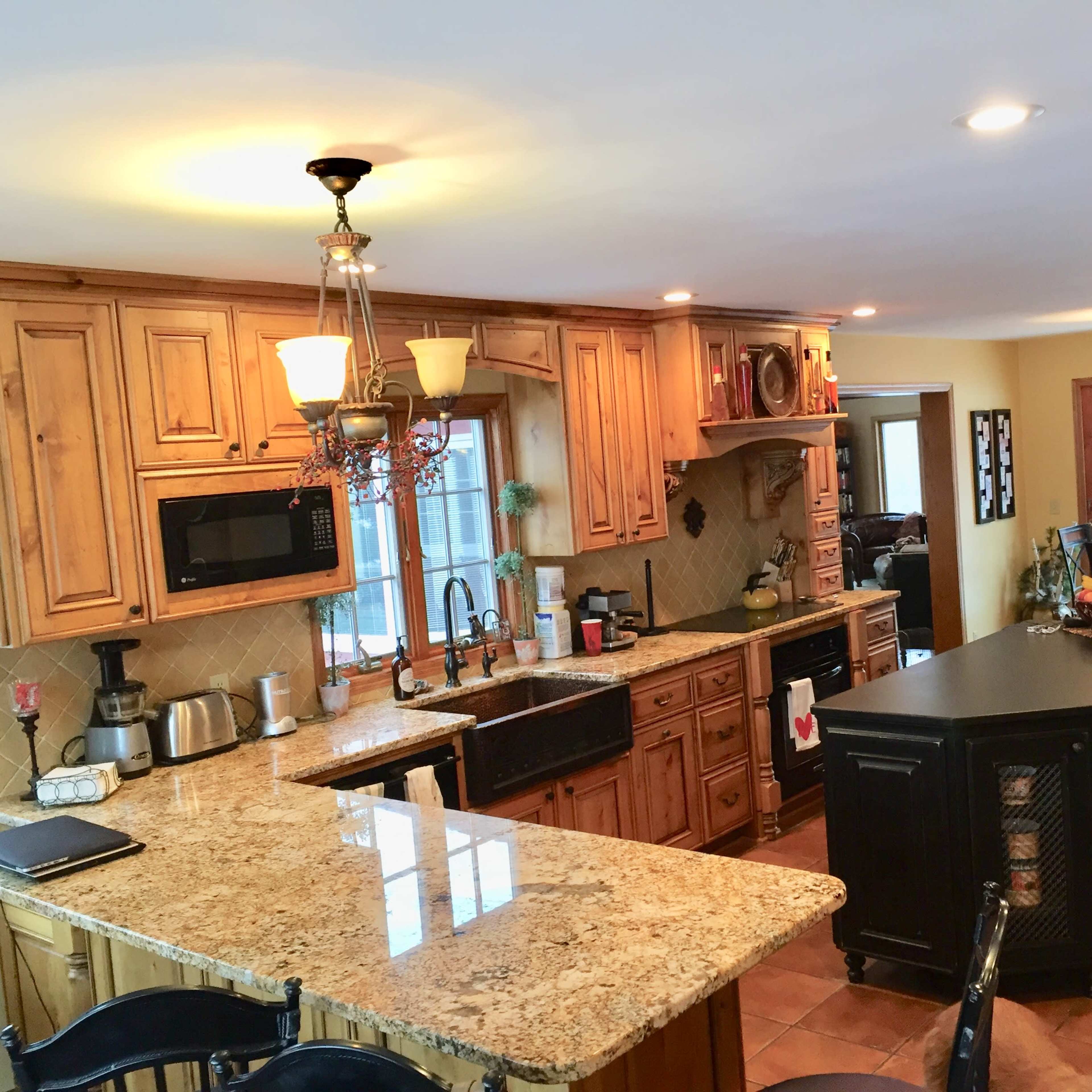 The kitchen features wooden cabinetry, granite countertops, and a central island with seating.