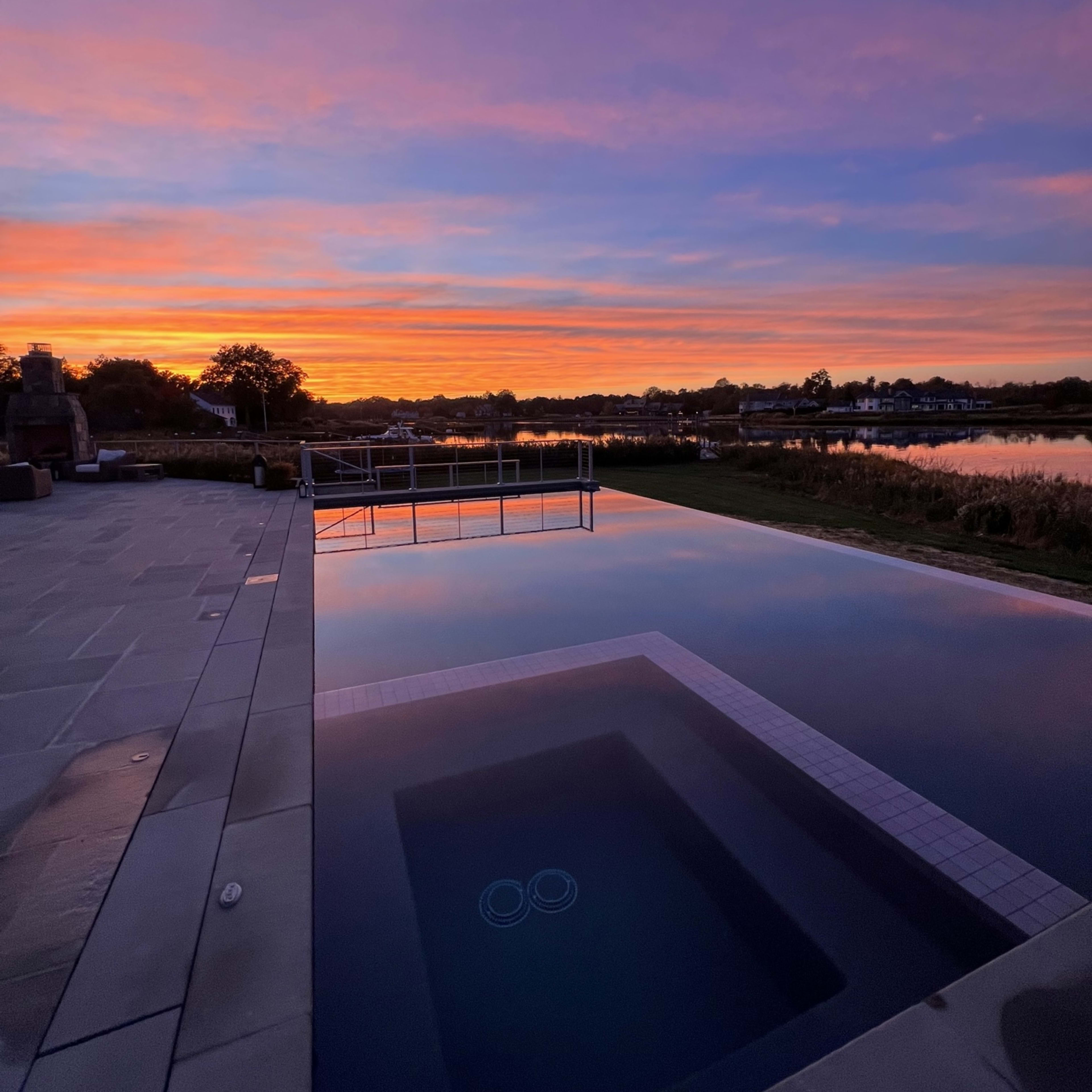 A swimming pool at sunset, with vibrant colors reflected in the water.