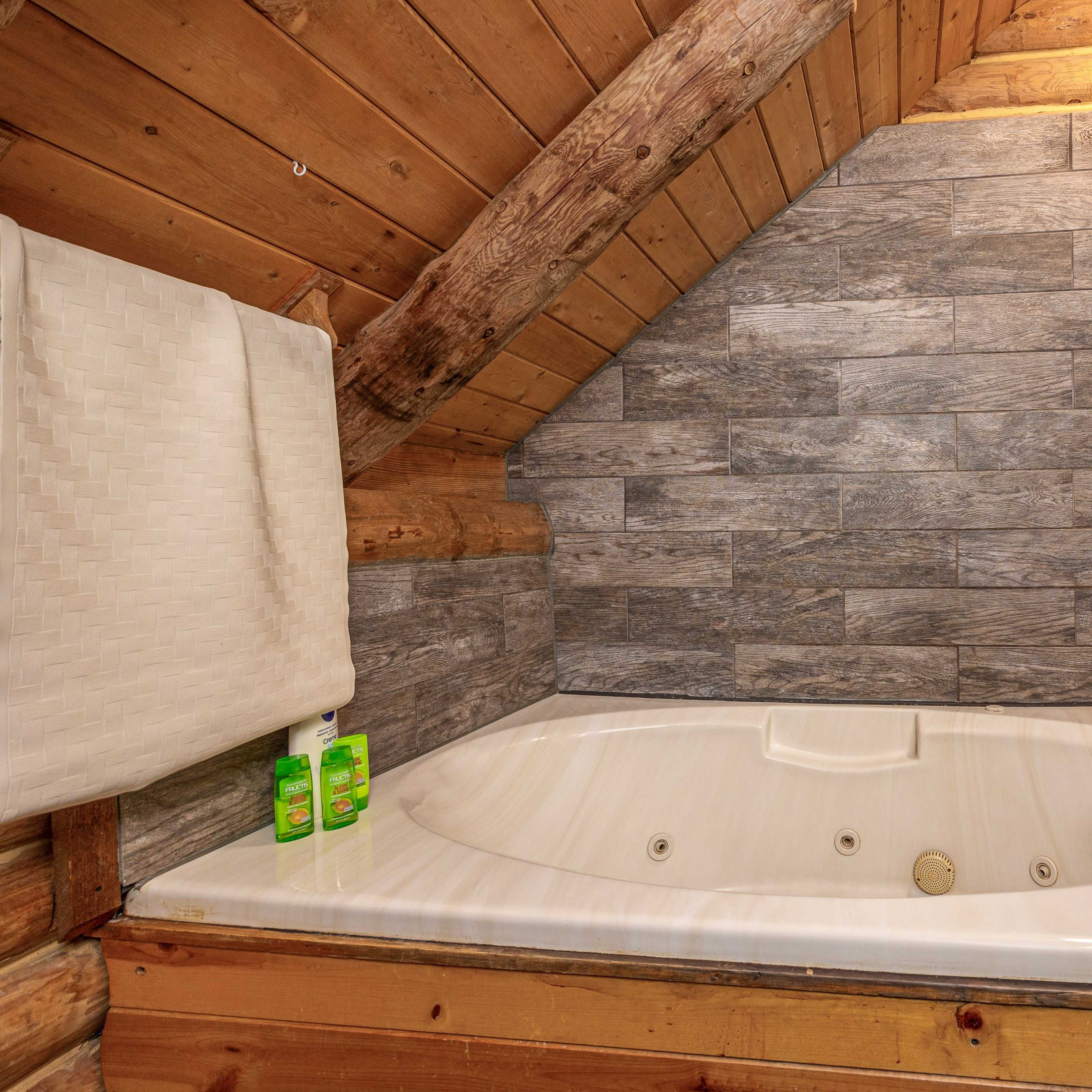 A wooden-paneled bathroom featuring a corner jacuzzi tub with a shower head above, set against tiled walls.