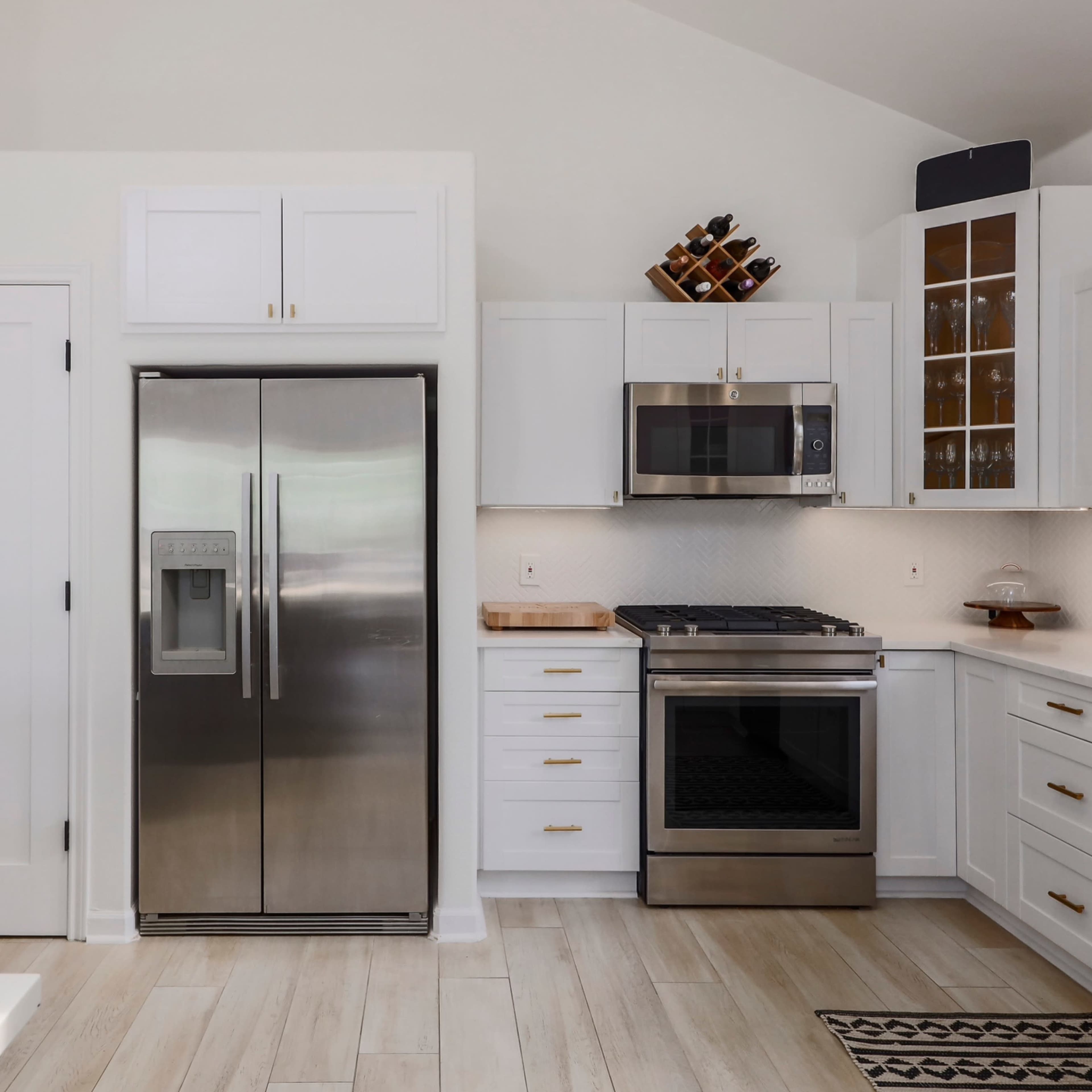 The kitchen features stainless steel appliances, white cabinetry, and a wooden countertop.
