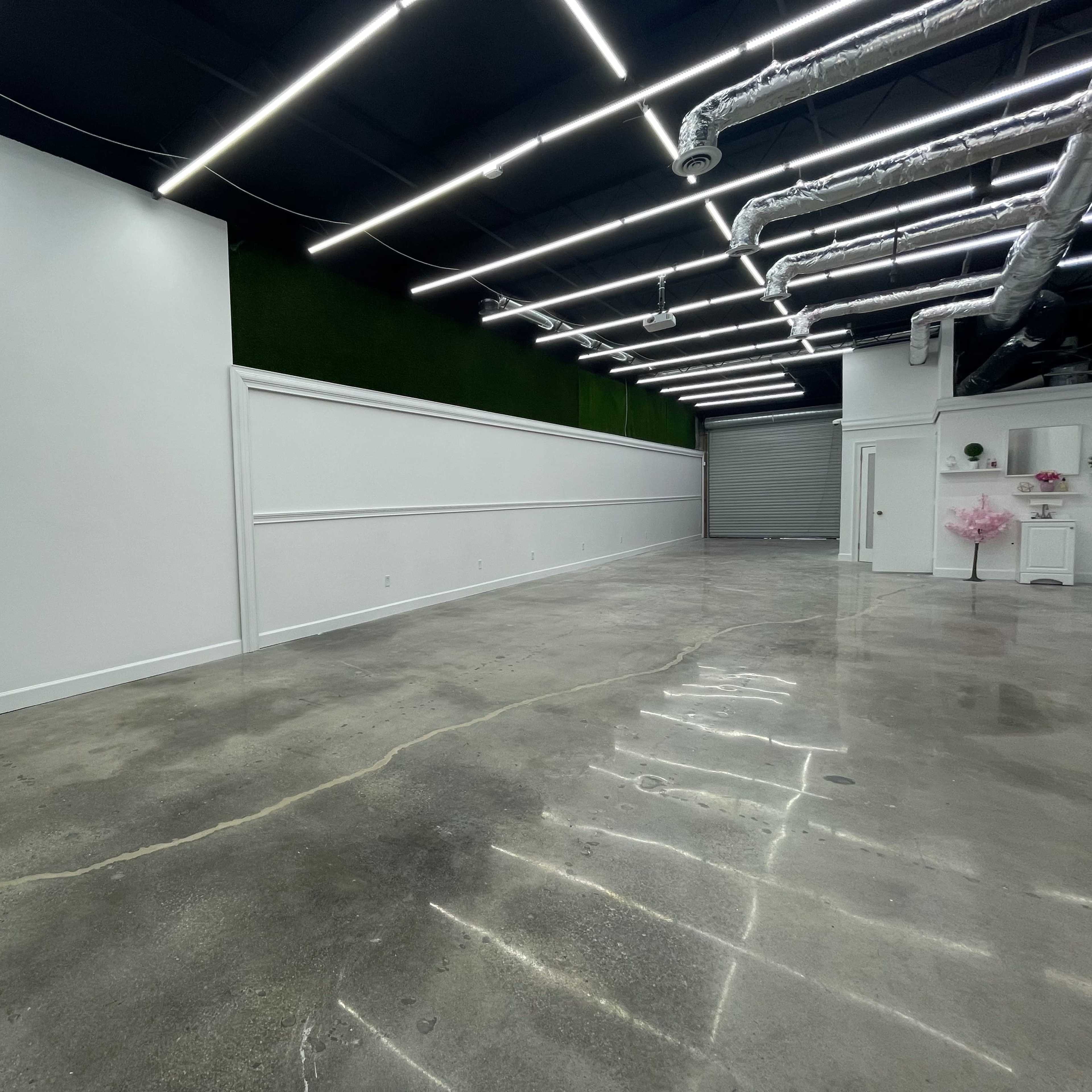 A spacious, minimally decorated interior with concrete floors and a white wall featuring decorative molding.