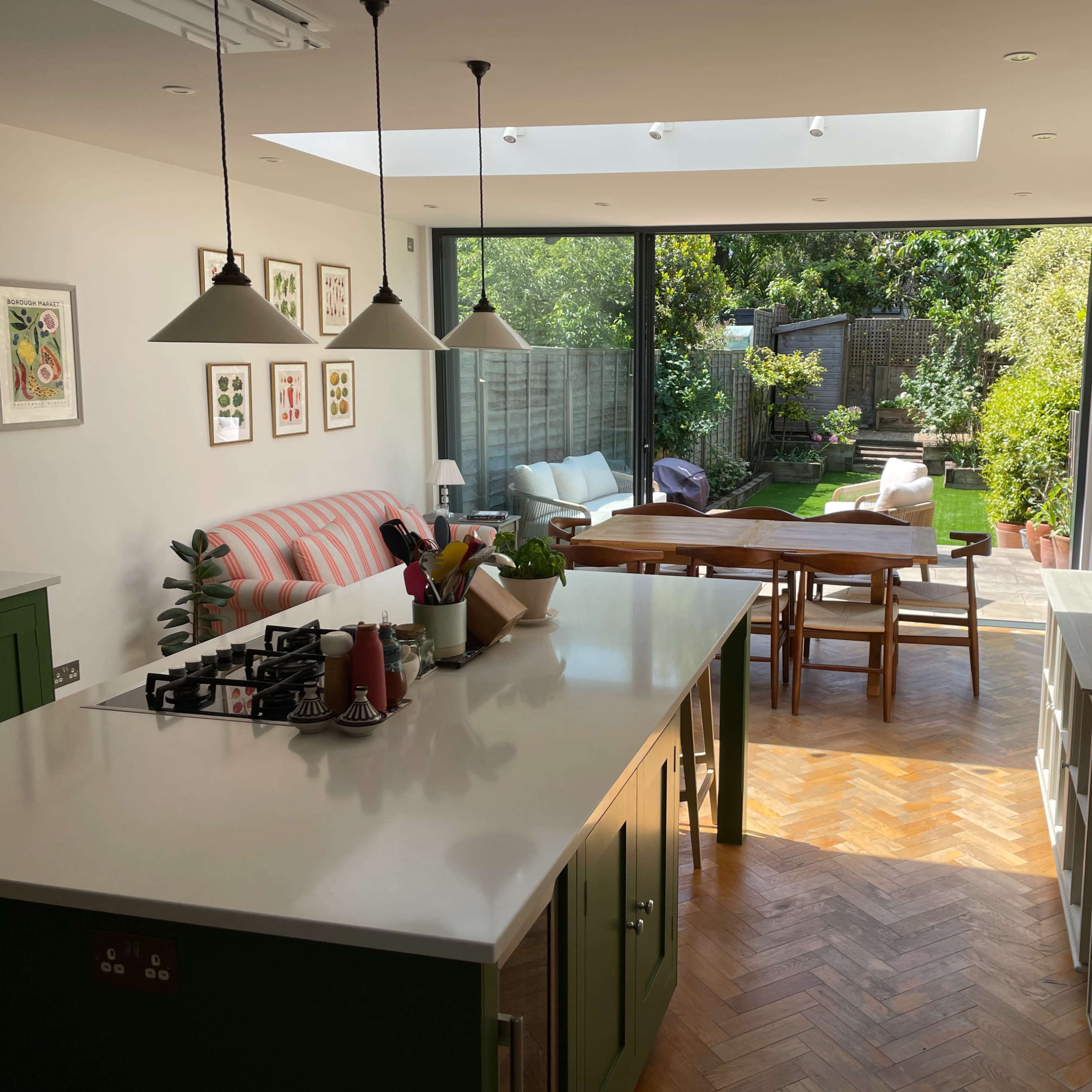 A modern kitchen with a large island opens to a well-maintained garden through sliding glass doors.