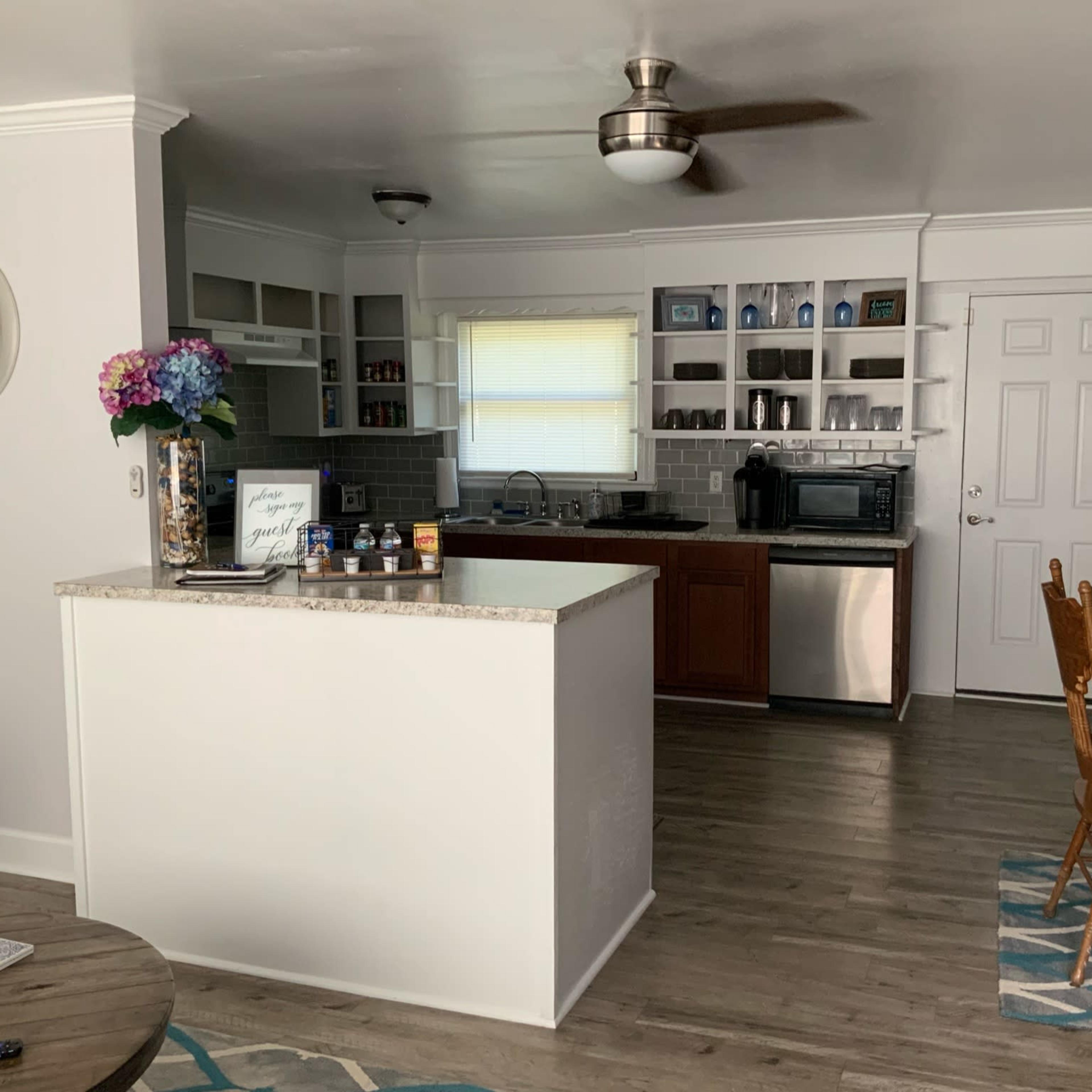 A modern kitchen with a central island, stainless steel appliances, wooden cabinets, and a dining area featuring a round table and chairs.