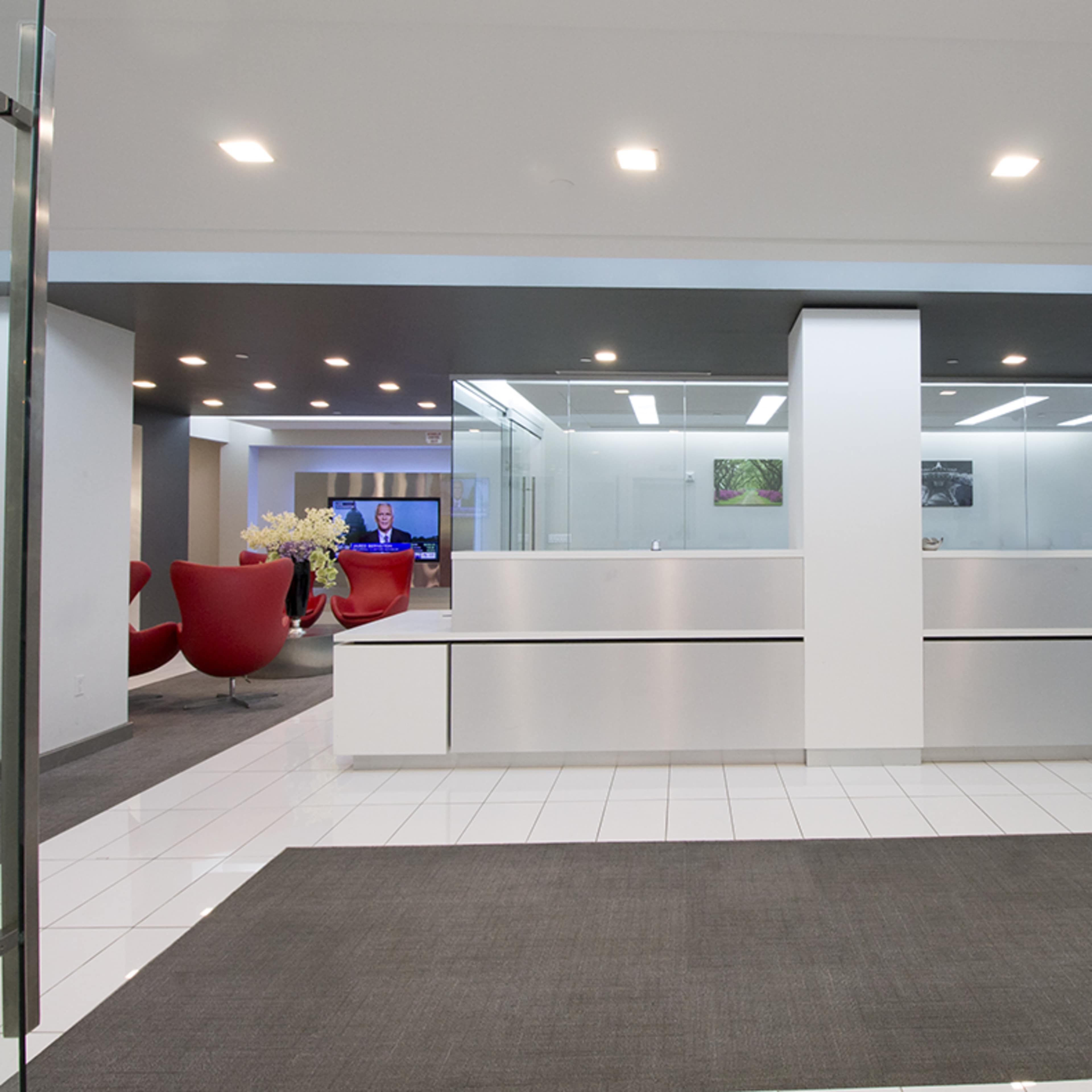 A modern reception area with a sleek front desk, large glass doors, and comfortable seating in the background.