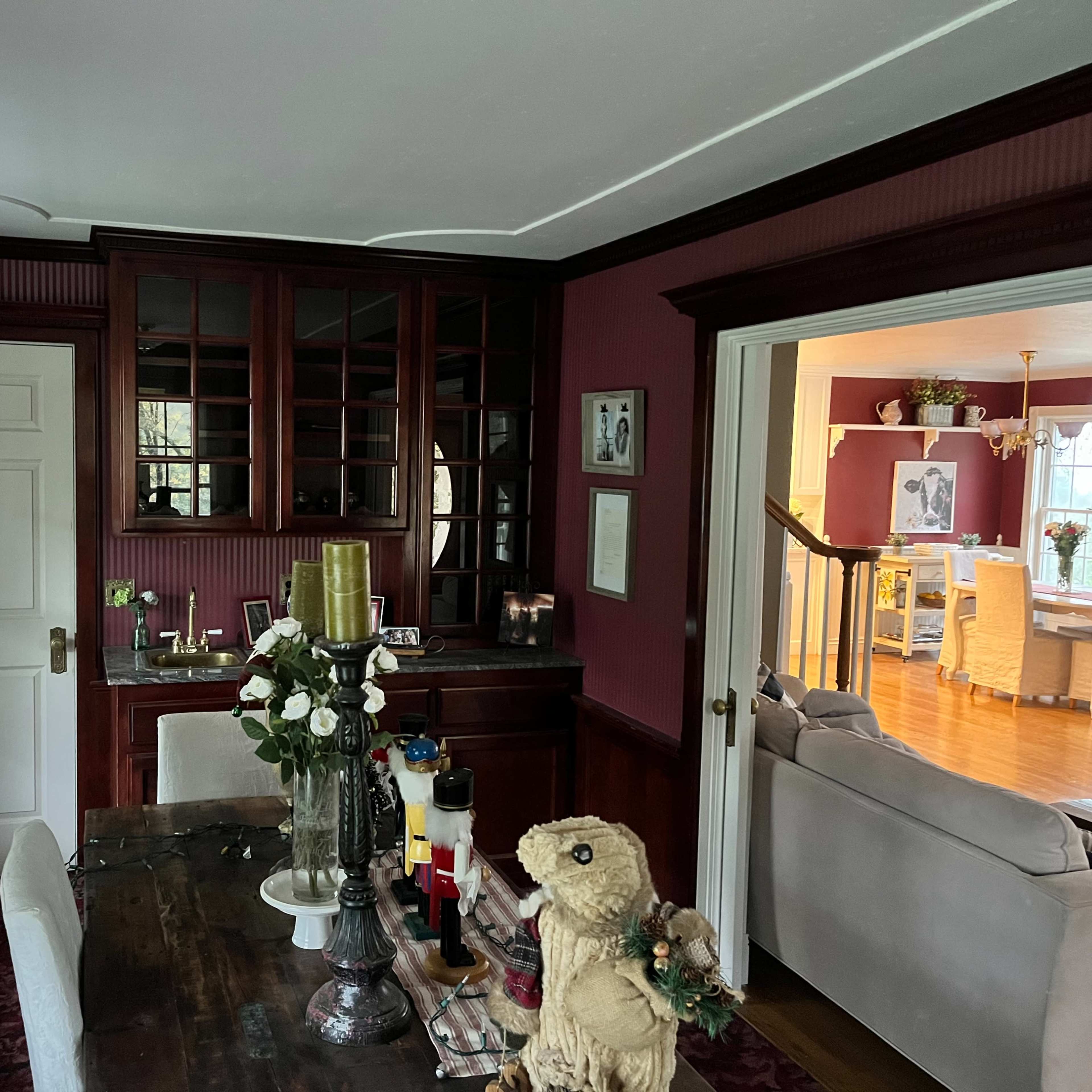 A dining area features a dark wood table surrounded by chairs, with a built-in cabinet and a view into a living space beyond.
