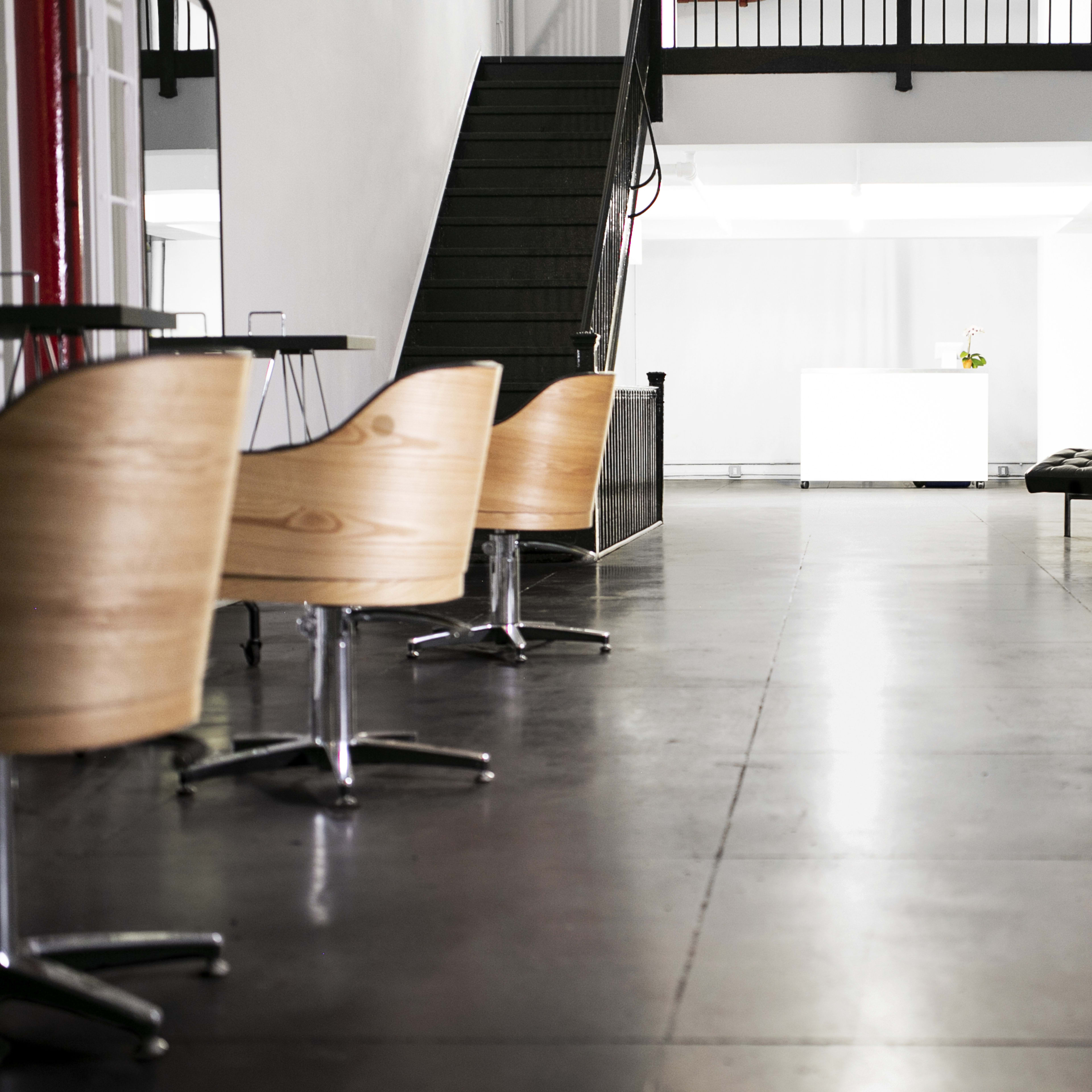 A modern indoor space with wooden chairs and a staircase leading to an upper level.