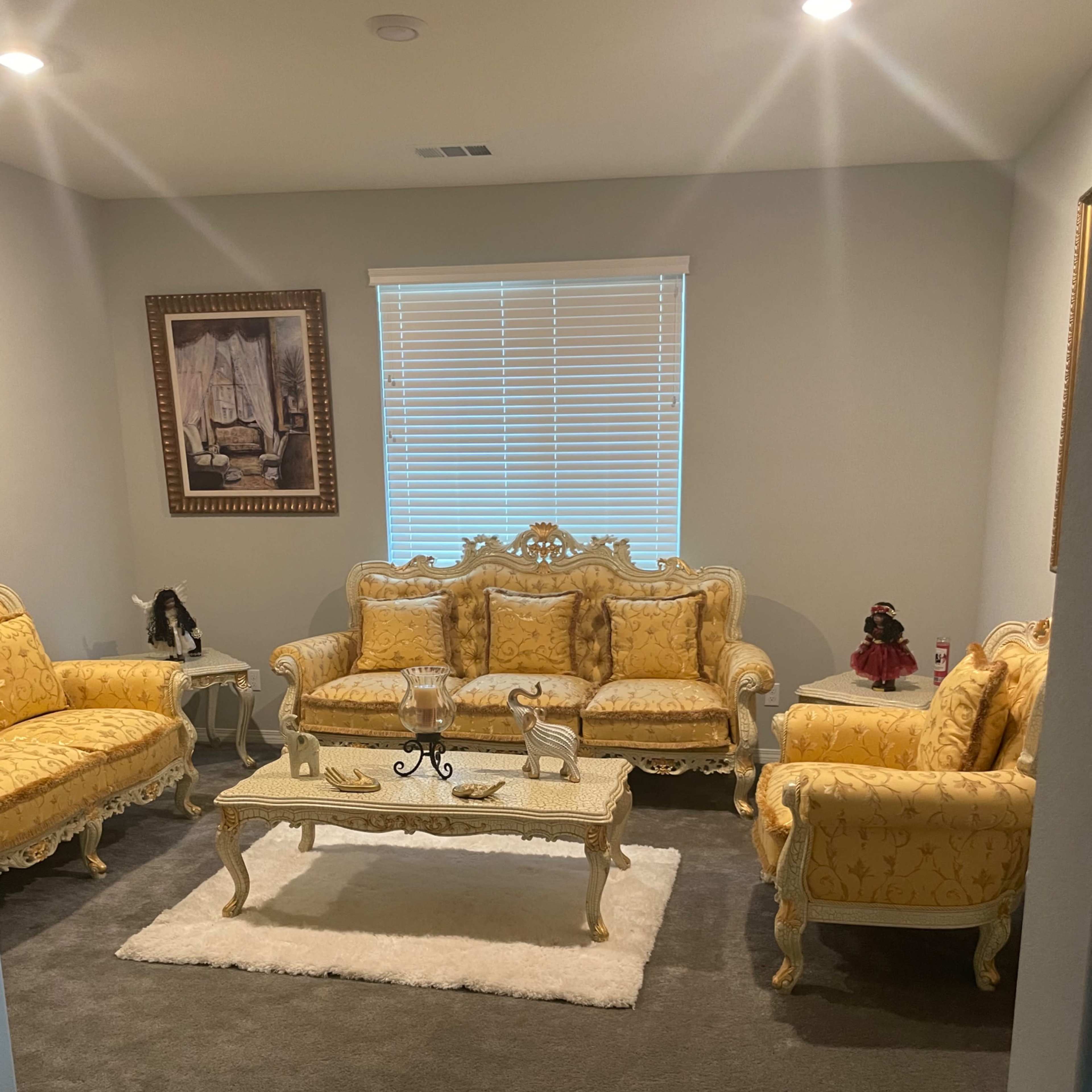 The room features two yellow upholstered sofas and a matching armchair arranged around a glass coffee table on a white rug.