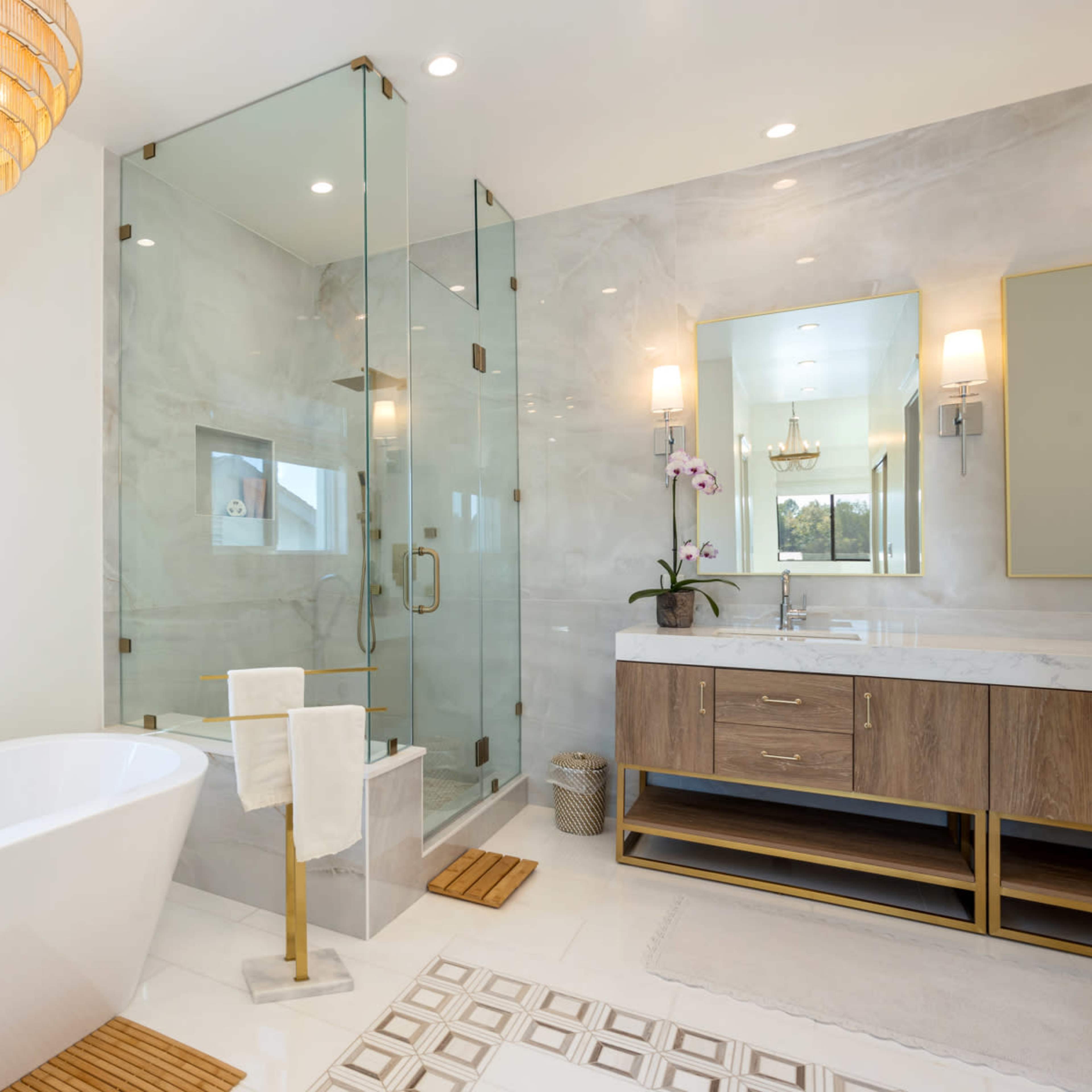 A modern bathroom with a freestanding bathtub, a glass shower enclosure, and a double vanity with a mirror.