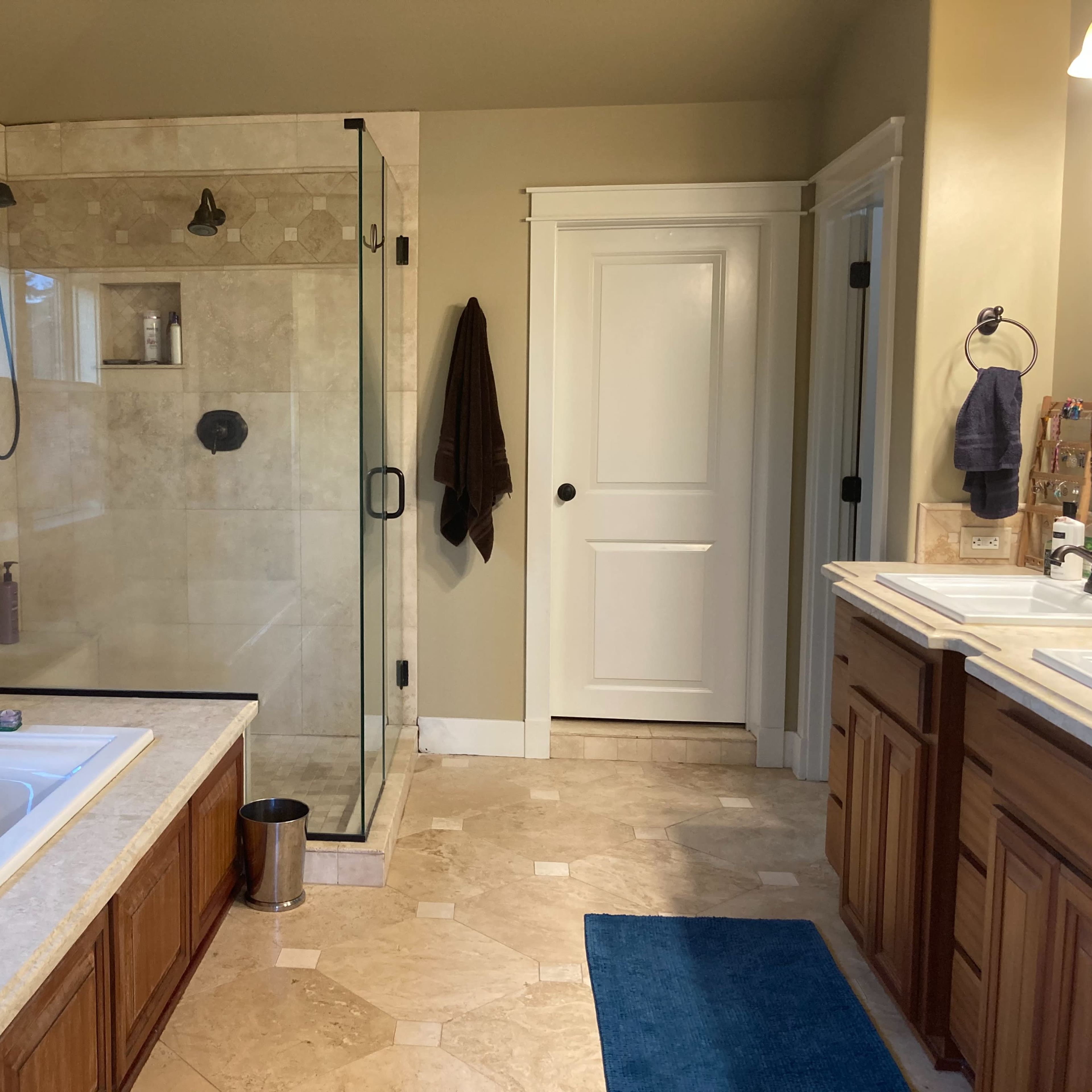 The bathroom features a glass-enclosed shower, a large jetted tub, and wooden cabinetry with dual sinks.